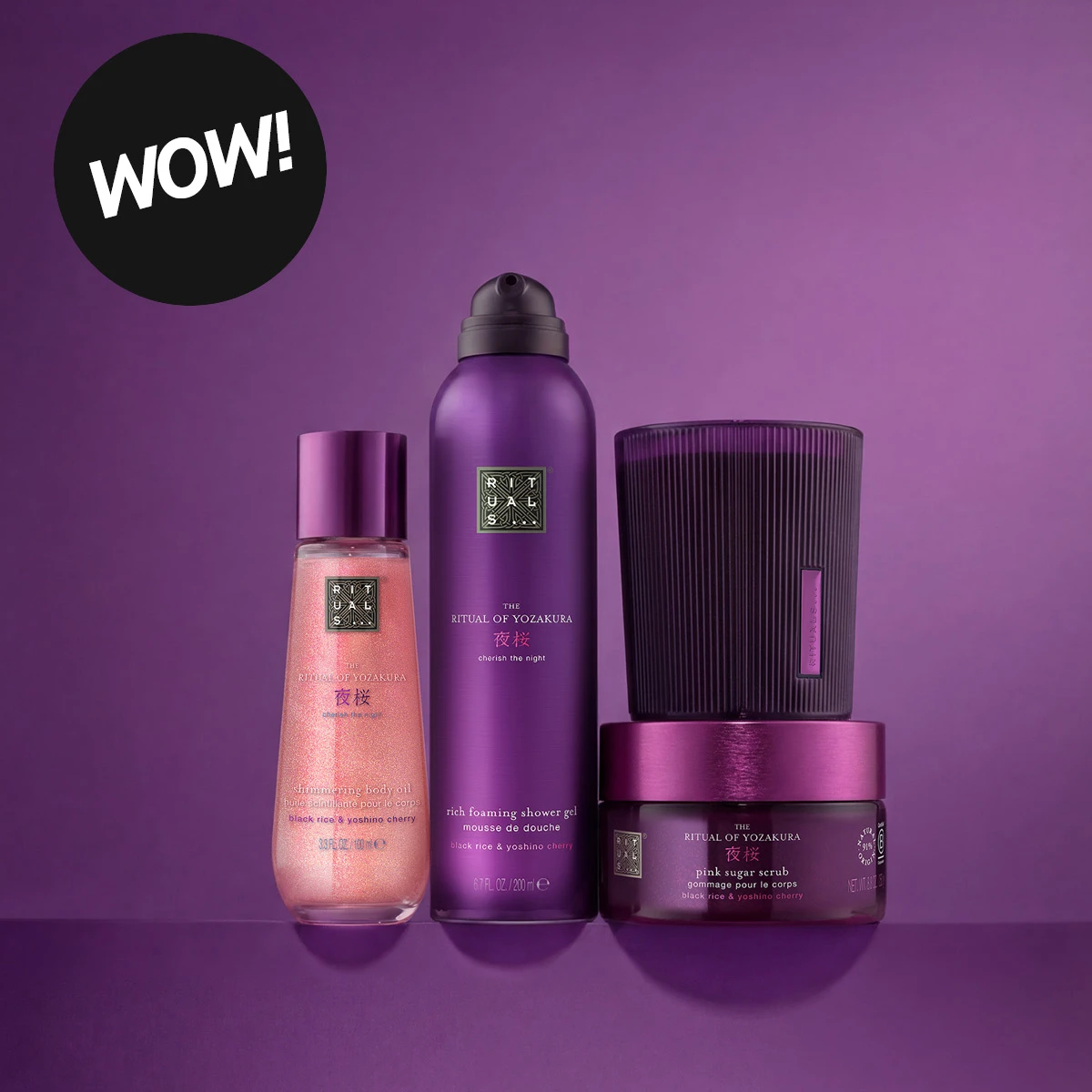 Fire lilla og rosa kroppsprodukter fra Rituals The Ritual of Yozakura: Shimmering Body Oil, Rich Foaming Shower Gel, Pink Sugar Scrub og en mørkelilla beholder, mot lilla bakgrunn. Synlig tekst inkluderer «cherish the night», «black rice & yoshino cherry» og «WOW!».