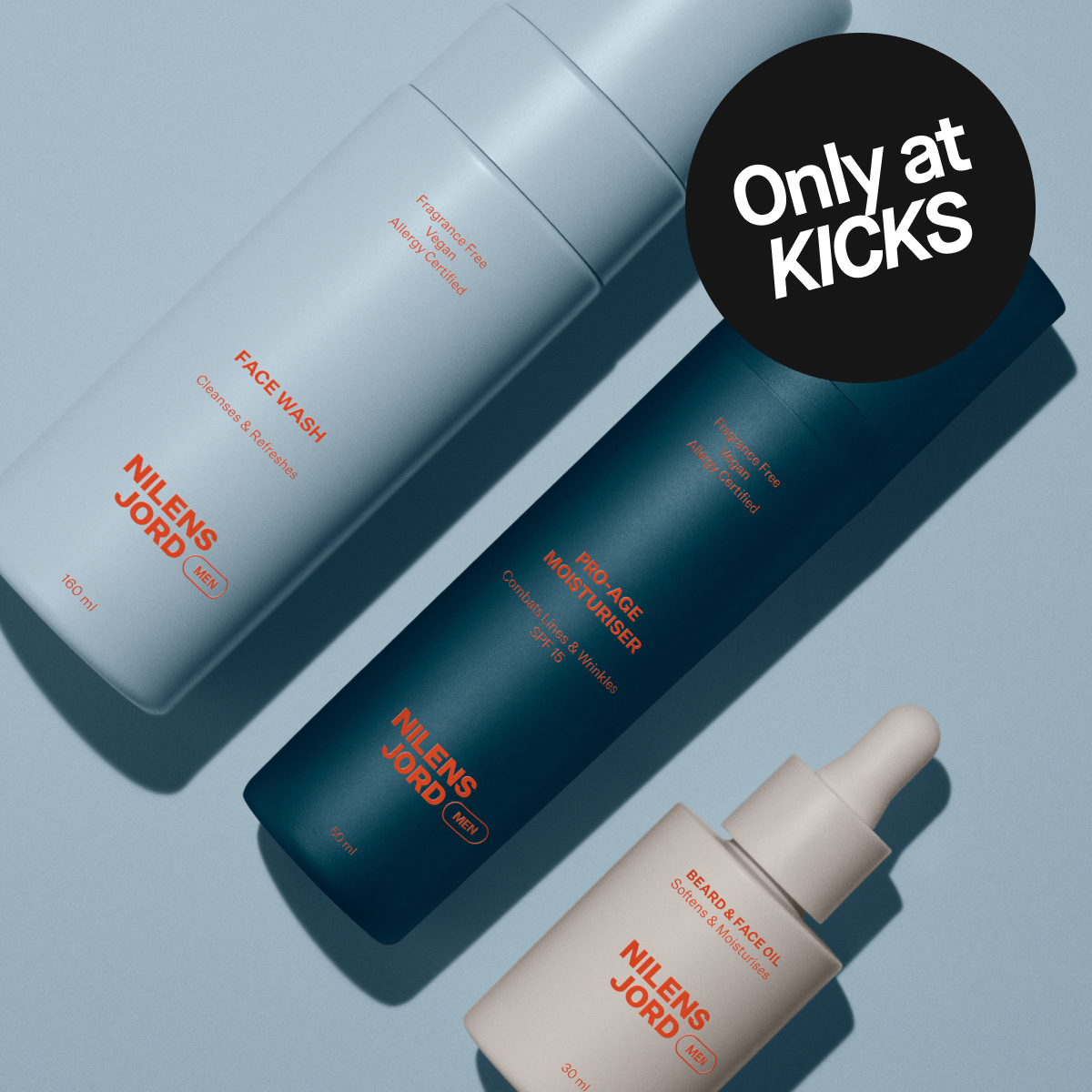 Tre Nilens Jord Men hudpleieprodukter ligger på en lys blå bakgrunn sammen med en svart sirkel med teksten “Only at KICKS”. Produktene er Face Wash 160 ml, Pro-Age Moisturiser SPF 15 50 ml og Beard & Face Oil 30 ml med oransje tekst som beskriver produktene som fragrance free, vegan og allergy certified.
