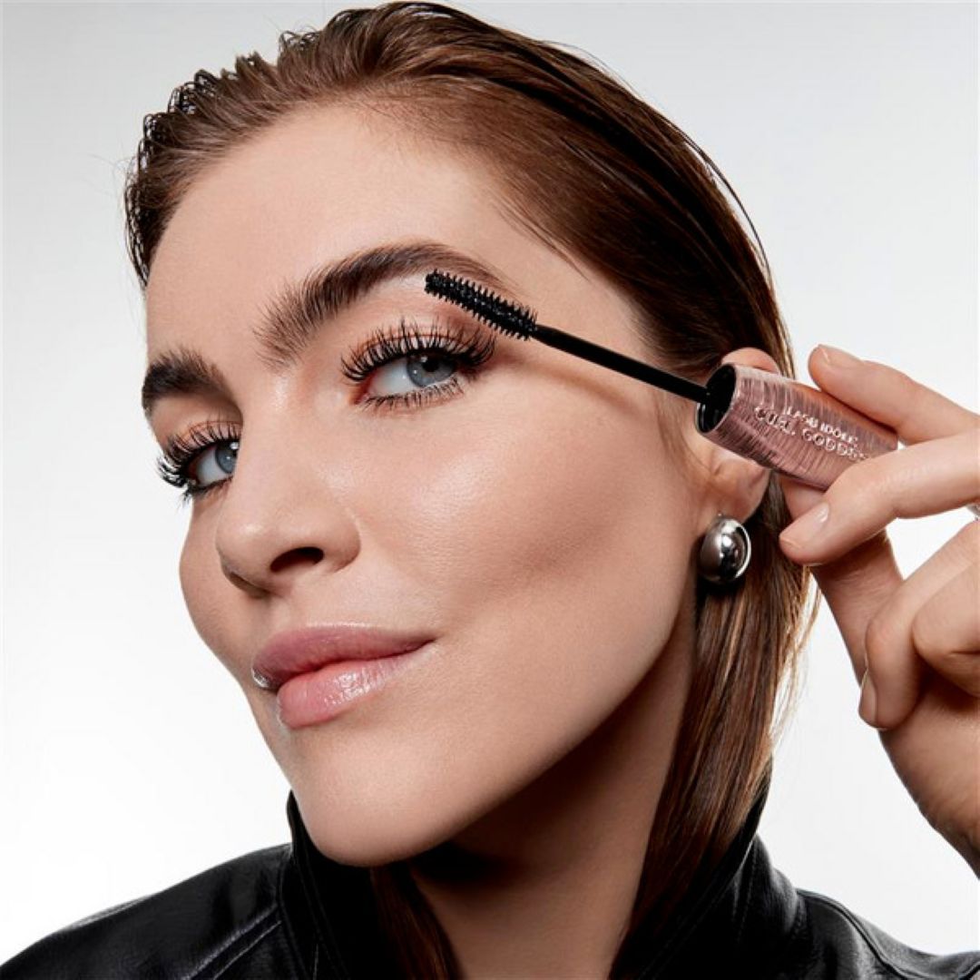 Närbild av en person som applicerar Lancôme Lash Idôle Curl Goddess mascara på övre fransar med synlig borste och produkttext på hylsan.