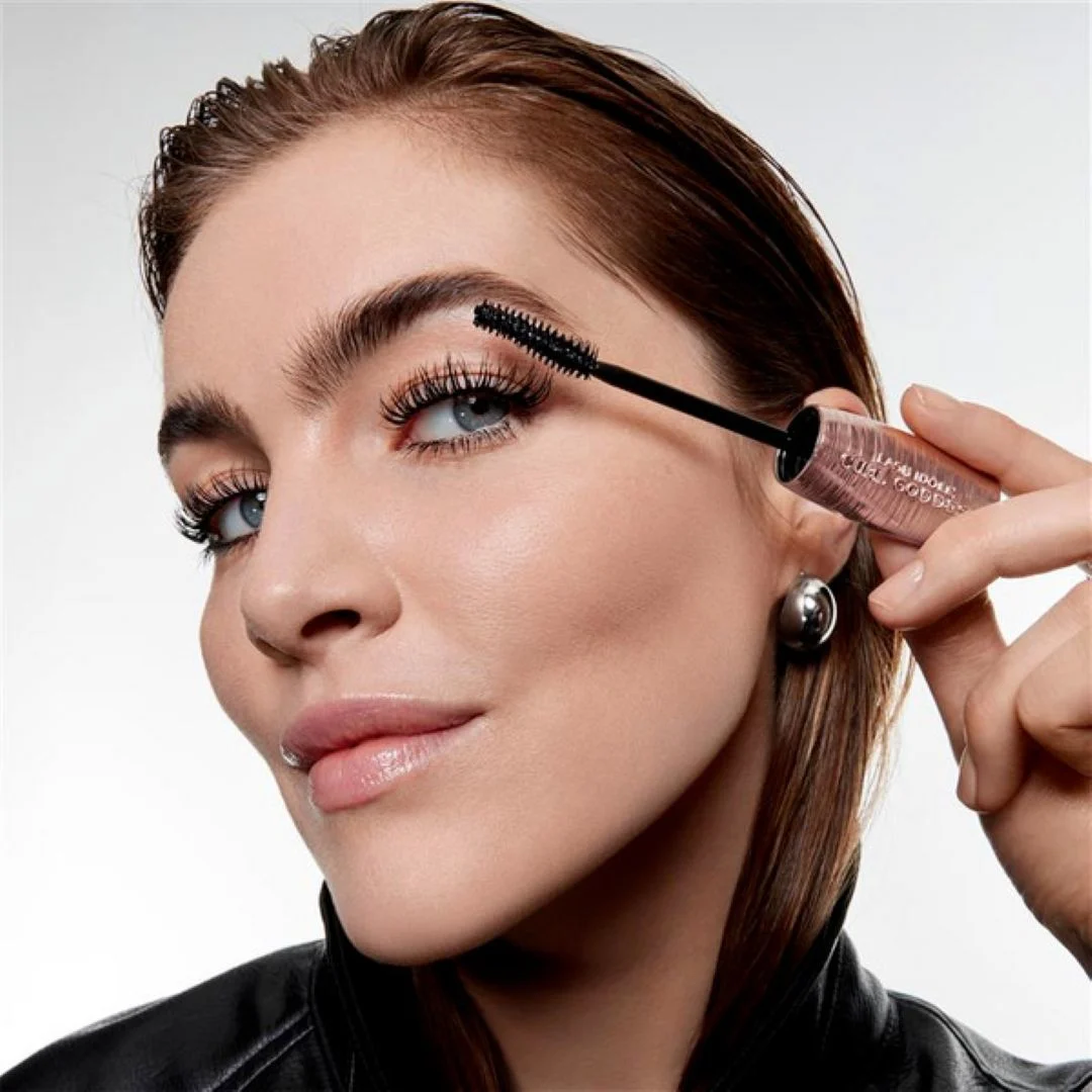 Lähikuva henkilöstä levittämässä Lancôme Lash Idôle Curl Goddess -ripsiväriä yläripsiin, harja ja tuoteteksti näkyvät hylsyssä.