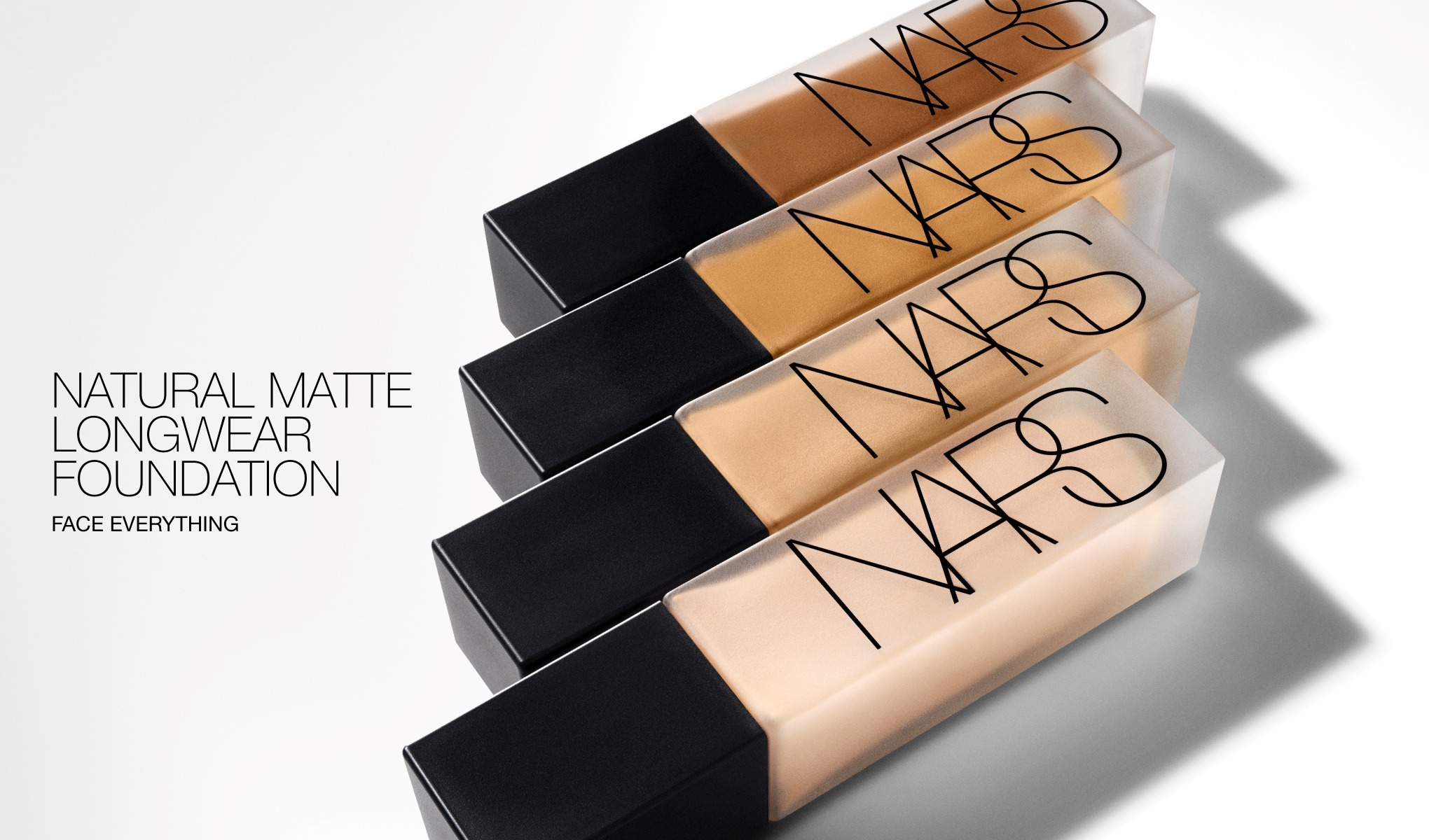Neljä NARS-meikkivoidepulloa mustalla korkilla ja tekstillä “NARS”. Vasemmalla näkyy teksti “NATURAL MATTE LONGWEAR FOUNDATION” ja “FACE EVERYTHING”, ja pullot näyttävät eri sävyjä nestemäistä meikkivoidetta.
