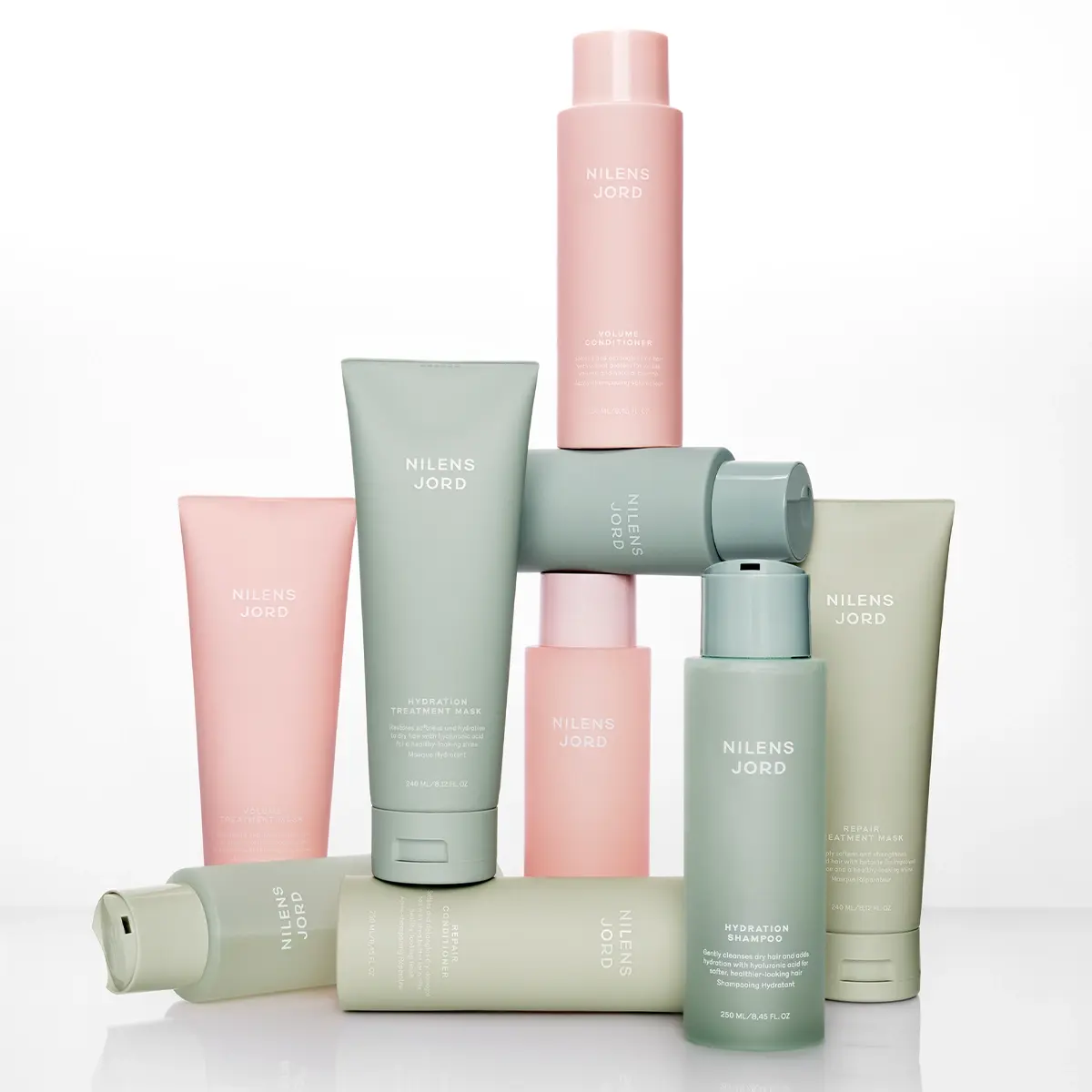 Nilens Jord hårpleieprodukter: sjampo, balsam og masker i lyserosa og salviegrønne flasker og tuber.