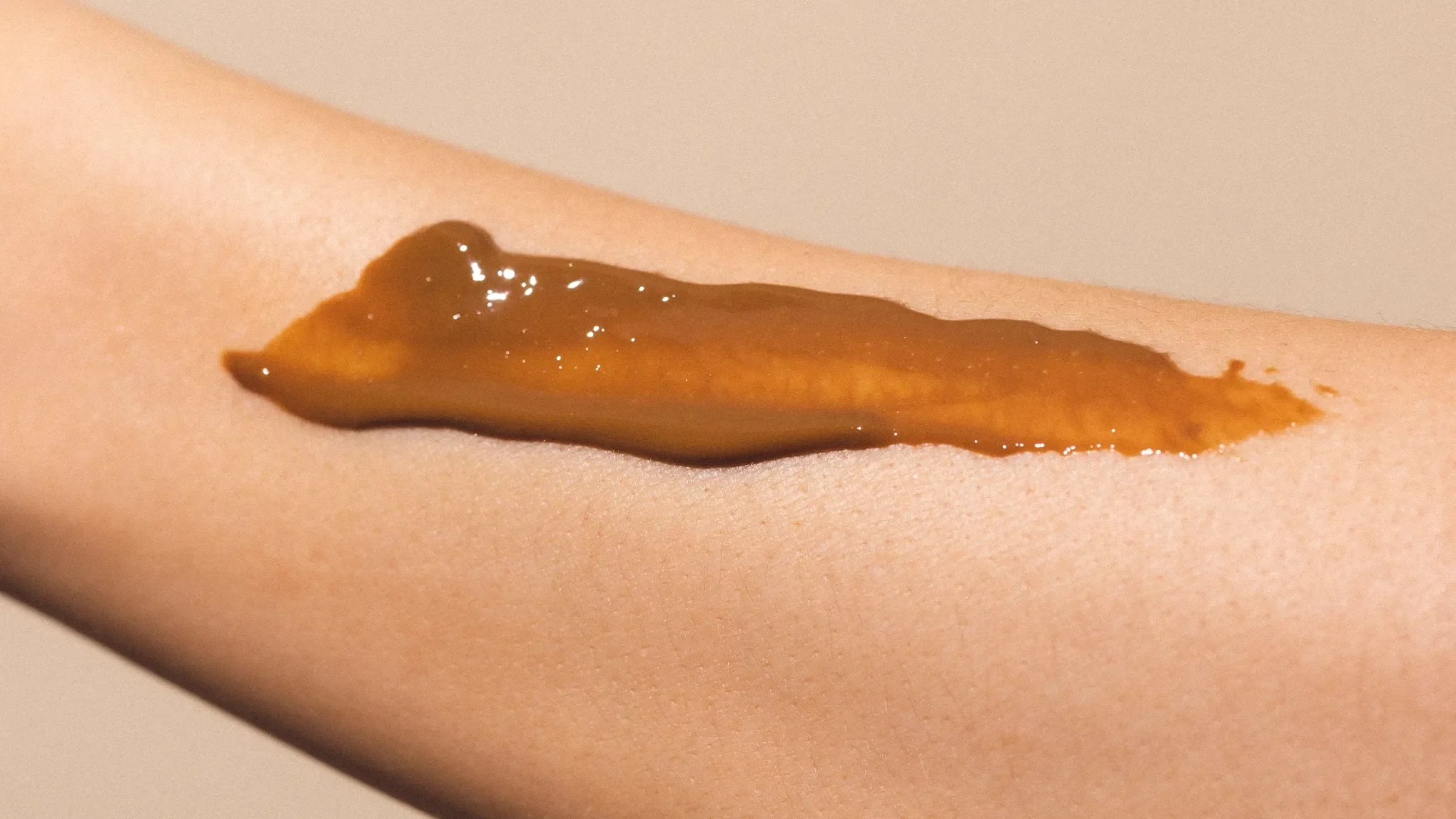 En närbild av en arm med en brun creme applicerad på huden