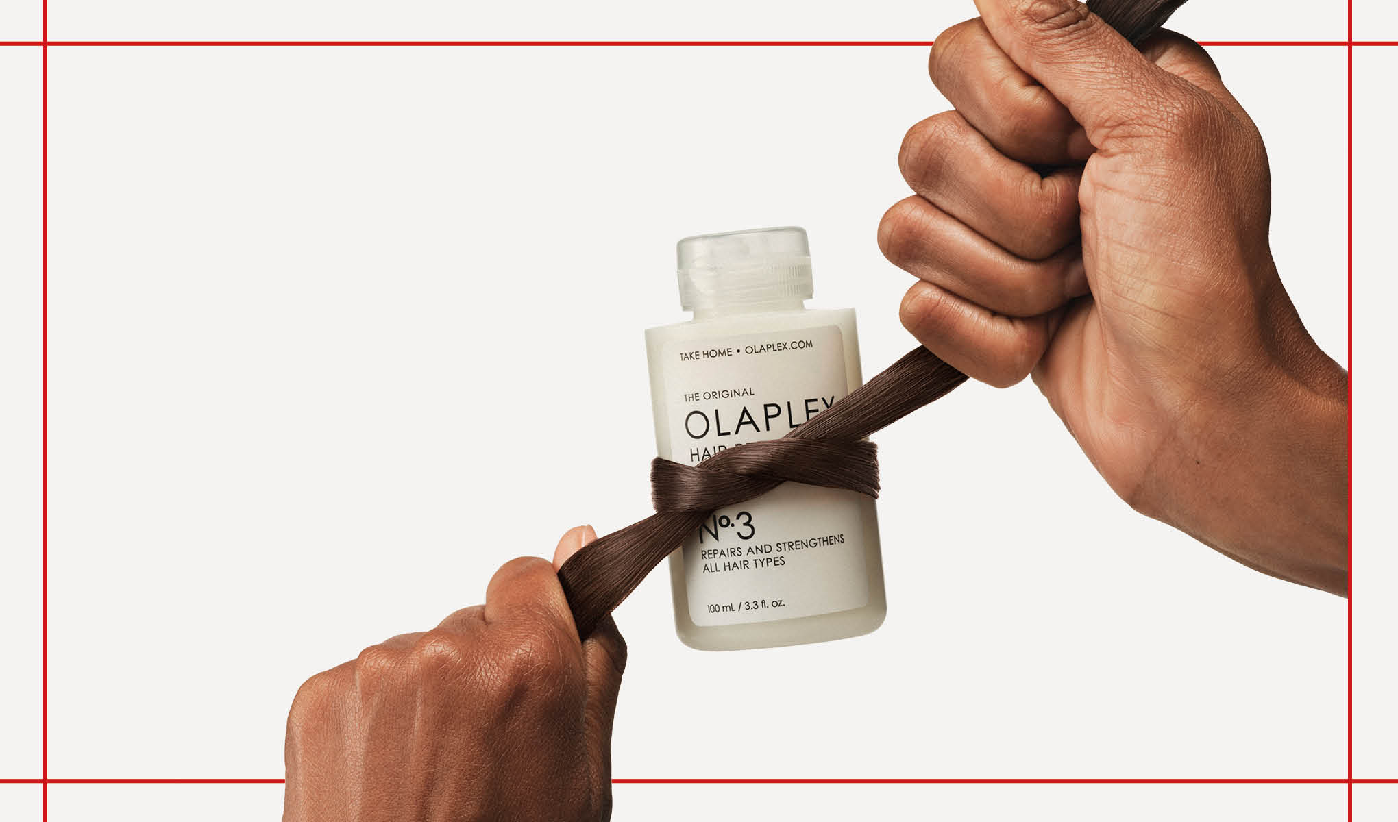 En vit flaska från Olaplex som hålls av två händer med en brun hårslinga virad runt flaskan. Bakgrunden är vit med röda linjer.