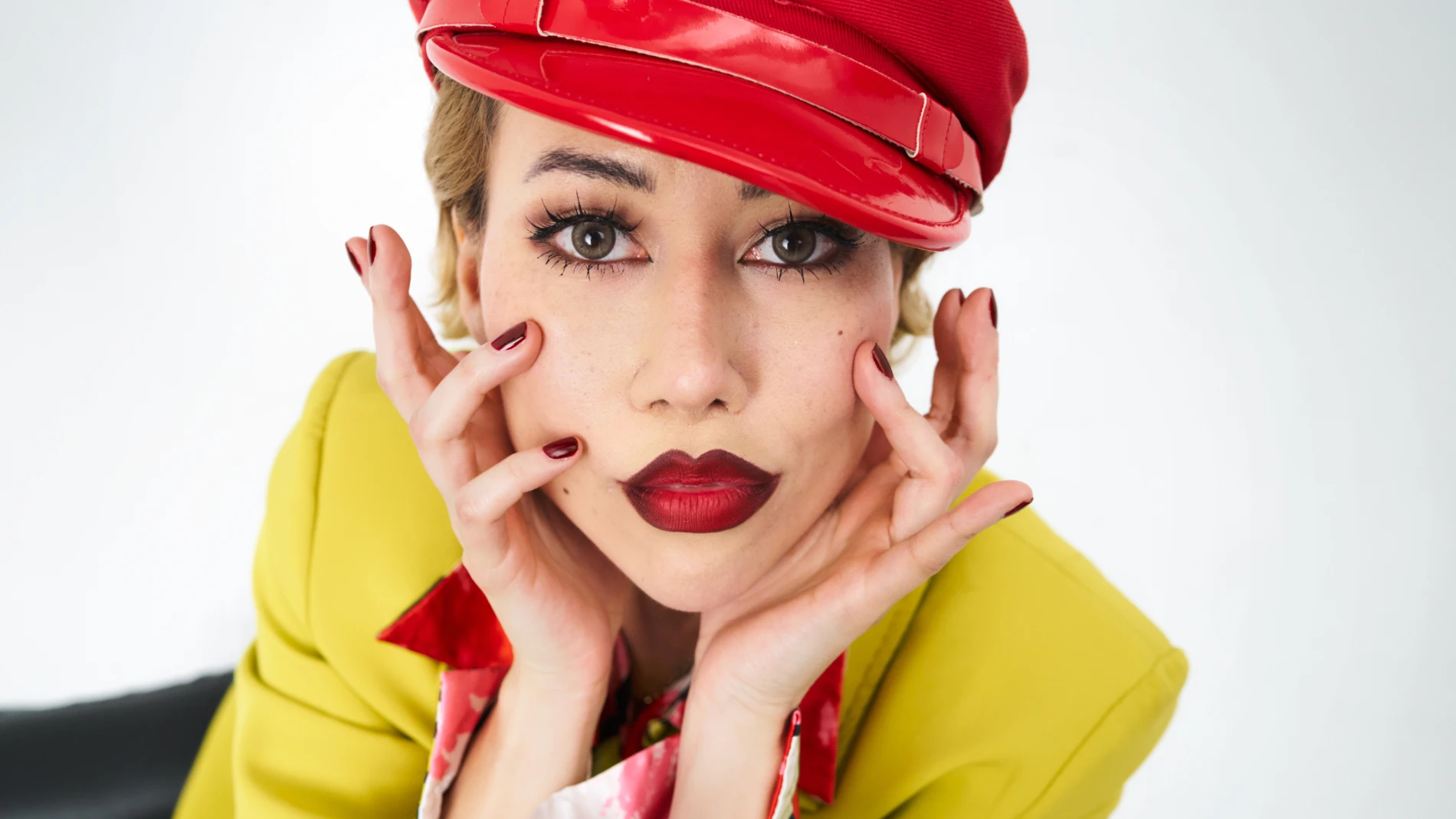 Henkilö, jolla on punainen hattu ja keltainen takki, pukeutunut värikkäisiin vaatteisiin.