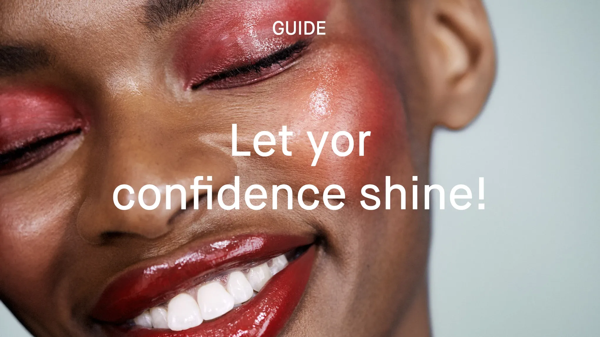 Lähikuva hymyilevästä henkilöstä, jolla on kiiltävä punainen luomiväri, poskipuna ja huulipuna. Kuvassa teksti "Let yor confidence shine!".