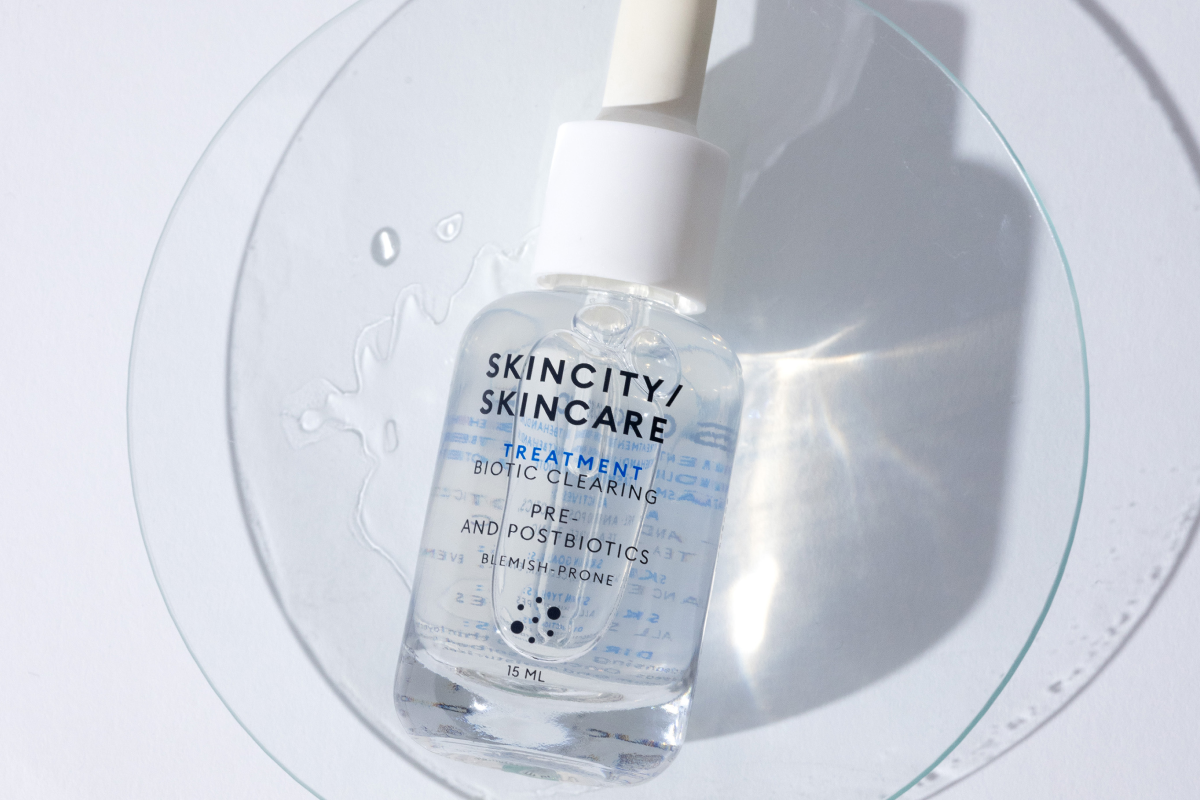 Nærbilde av en flaske Skincity Skincare Treatment Biotic Clearing på en glassplate.