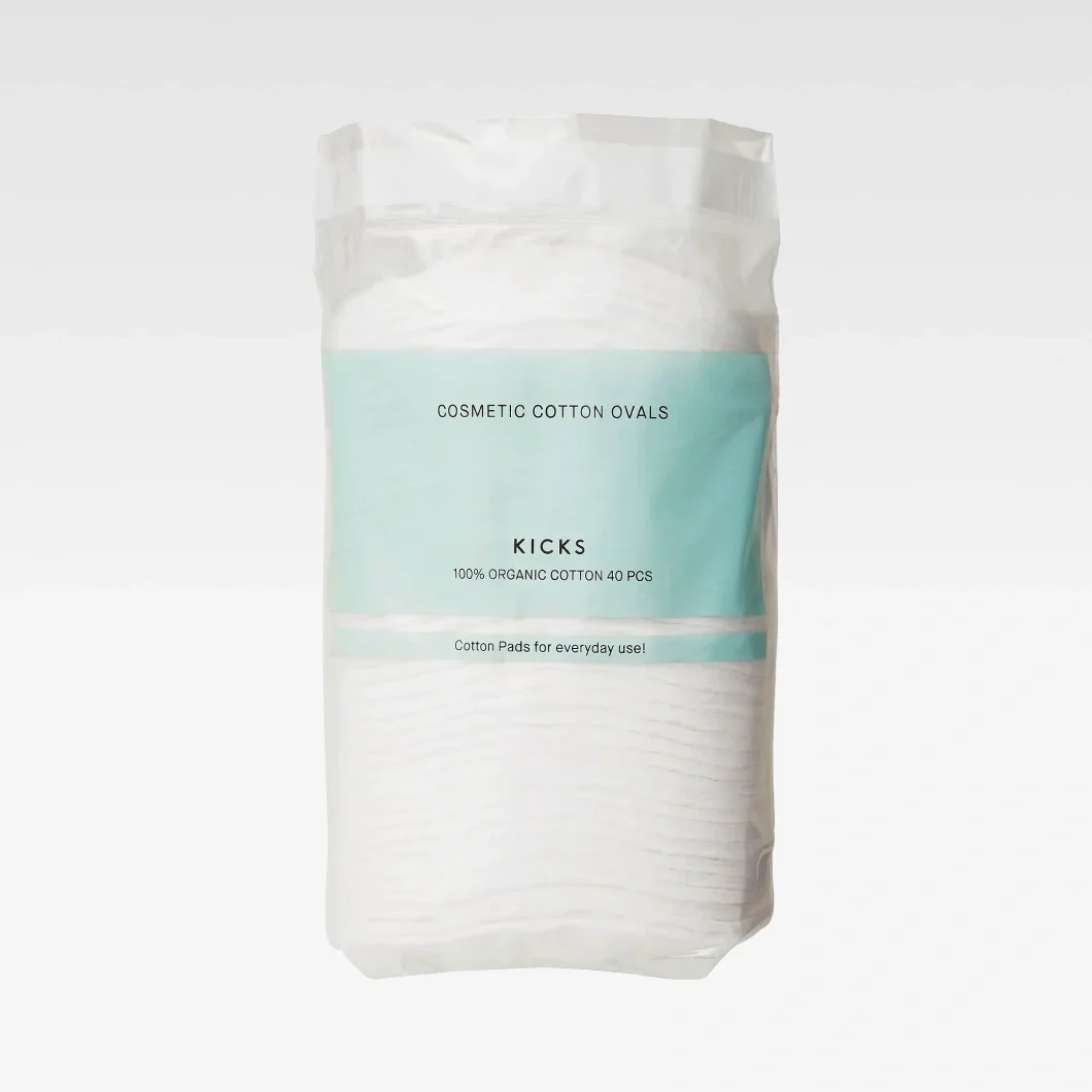 Förpackning med KICKS Cosmetic Cotton Ovals i vit plastförpackning med ljusblå etikett. Texten “COSMETIC COTTON OVALS”, “KICKS”, “100% ORGANIC COTTON 40 PCS” och “Cotton Pads for everyday use!” syns på förpackningen.