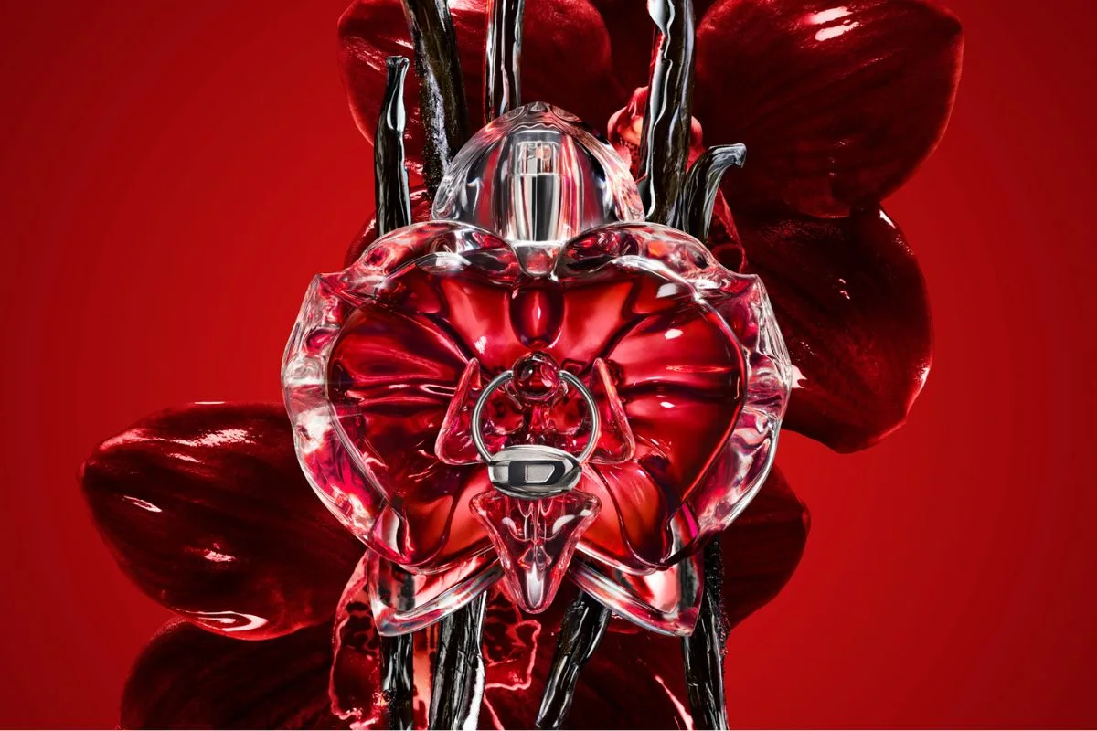 Diesel Loverdose Red Kiss-parfym mot röd bakgrund framför mörka orkidéer.
