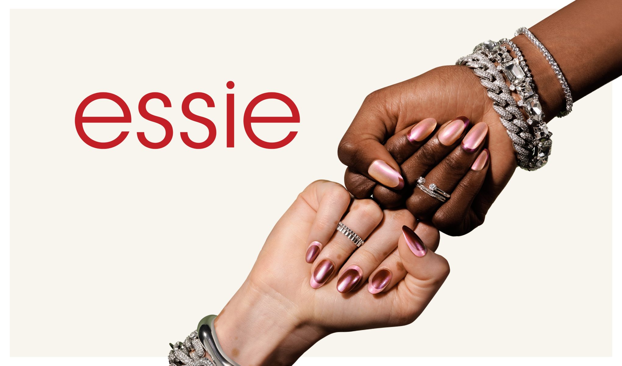 Två händer möts knoge mot knoge; metalliskt rosa naglar och texten ”essie” till vänster.