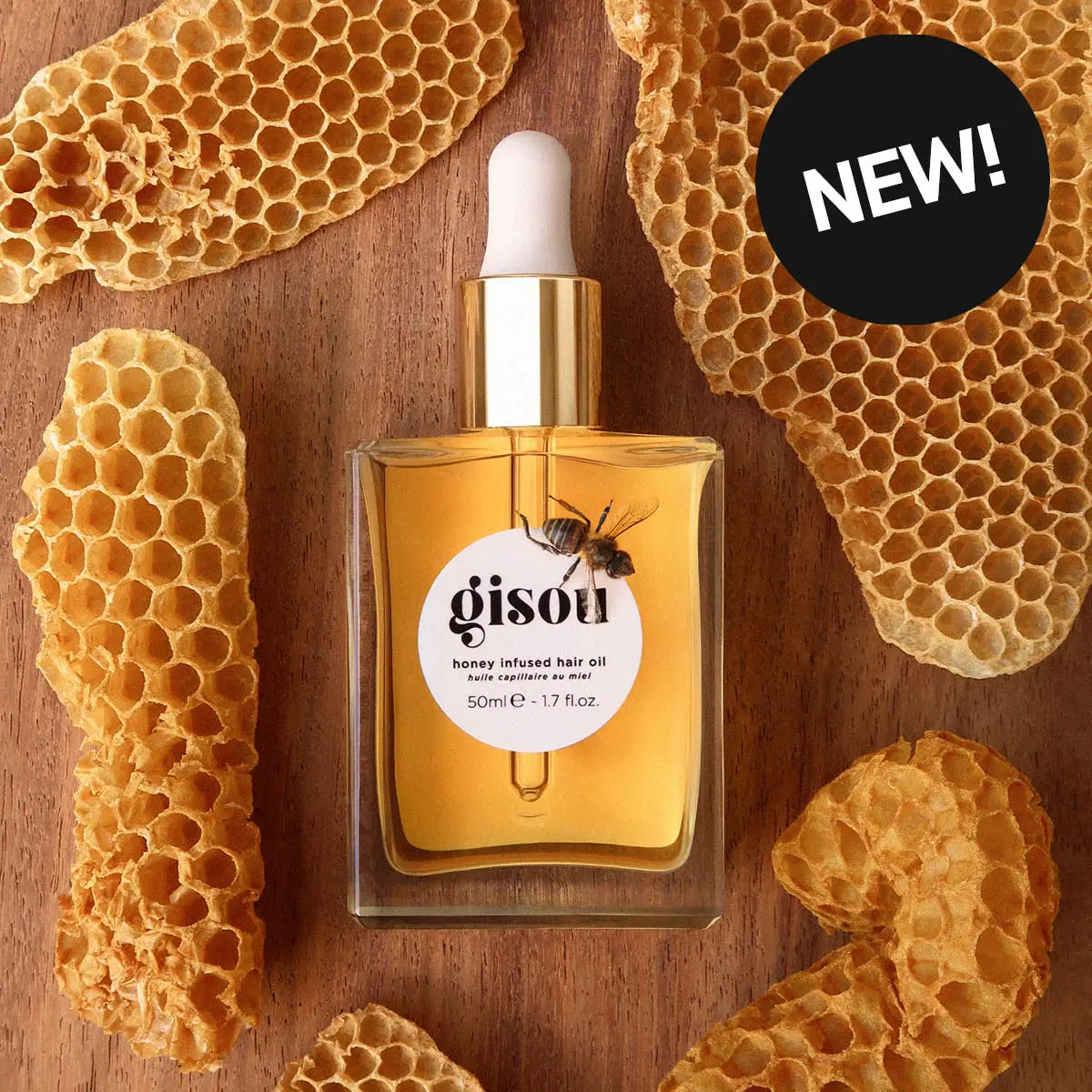 NY! Gisou honey infused hair oil (50ml) flaske, omgitt av bikake på en treoverflate.