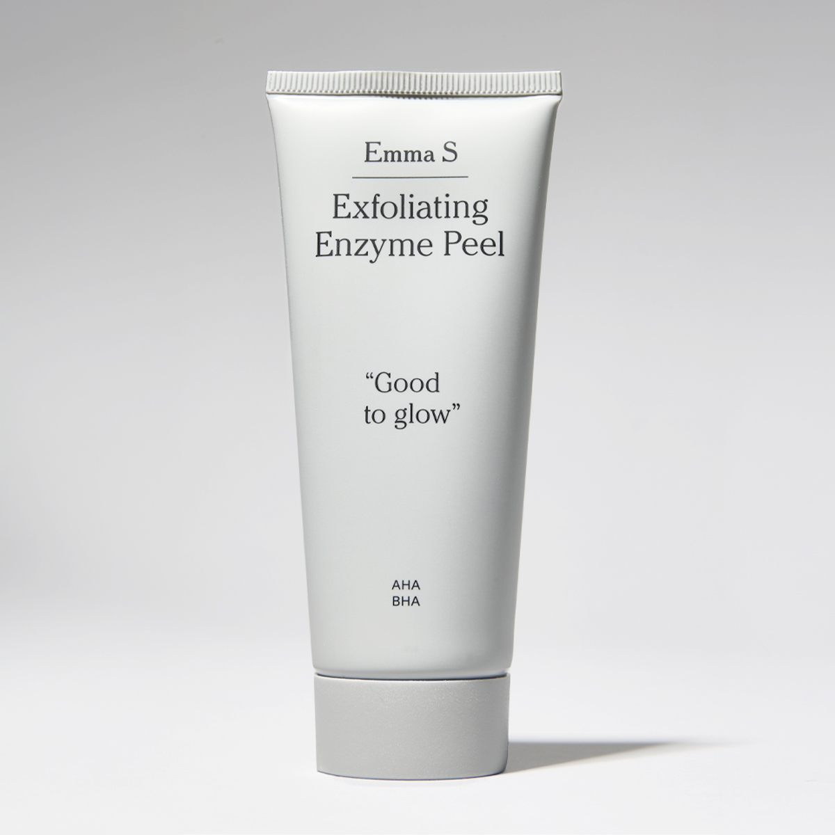Vit tub med ansiktspeeling från Emma S med texten “Exfoliating Enzyme Peel”, “Good to glow” och “AHA BHA” på en ljus bakgrund.