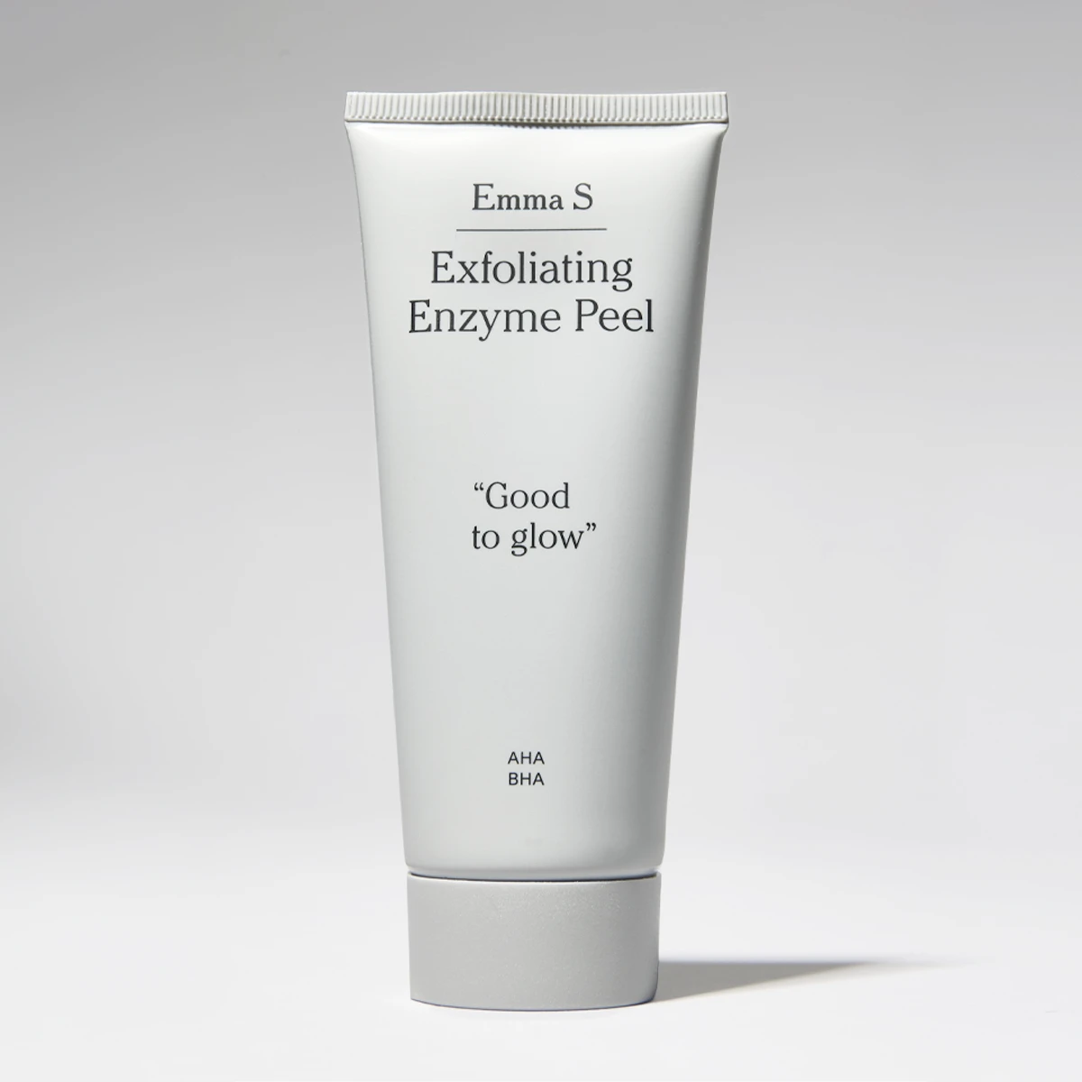 Valkoinen Emma S -kasvojen kuorintatuubi, jossa tekstit “Exfoliating Enzyme Peel”, “Good to glow” ja “AHA BHA” vaaleaa taustaa vasten.