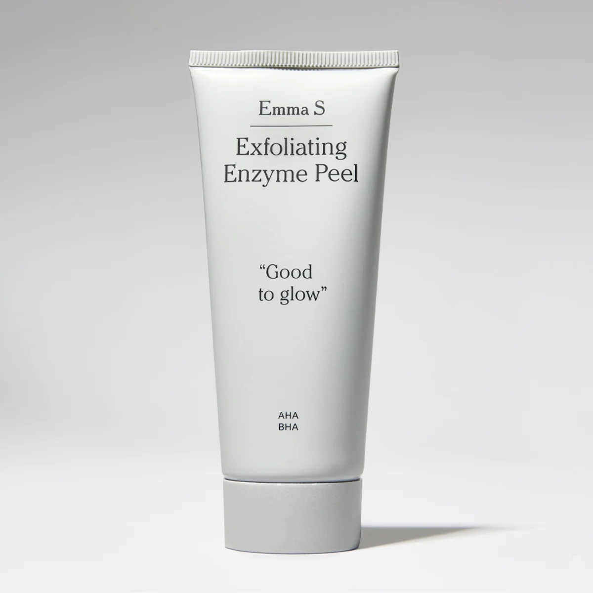 Valkoinen Emma S -kasvojen kuorintatuubi, jossa tekstit “Exfoliating Enzyme Peel”, “Good to glow” ja “AHA BHA” vaaleaa taustaa vasten.