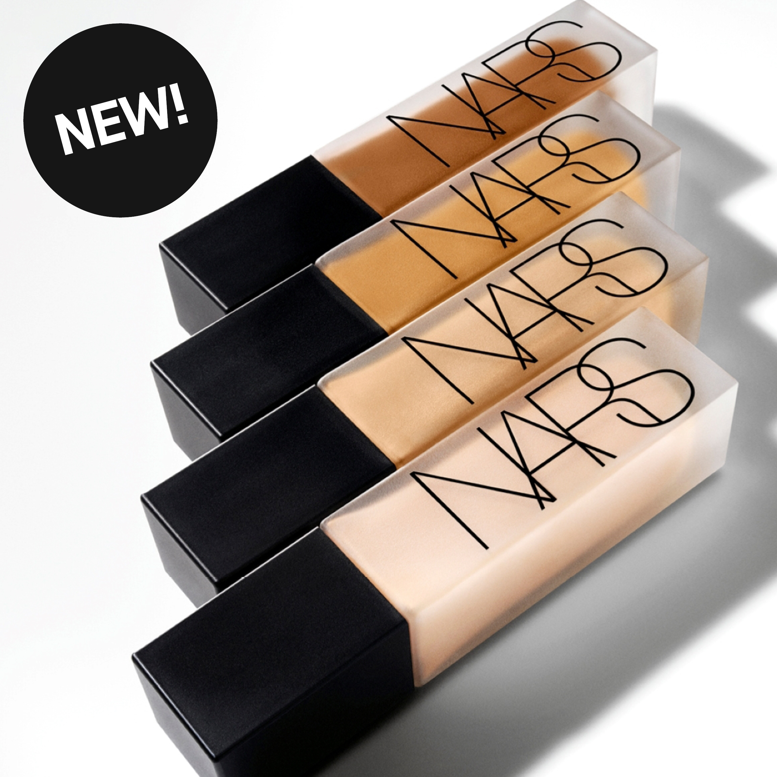 Neljä NARS-meikkivoidepulloa mustalla korkilla ja tekstillä “NARS”. Läpinäkyvät pullot näyttävät eri sävyjä meikkivoidetta sekä pyöreä merkki tekstillä “NEW!”.