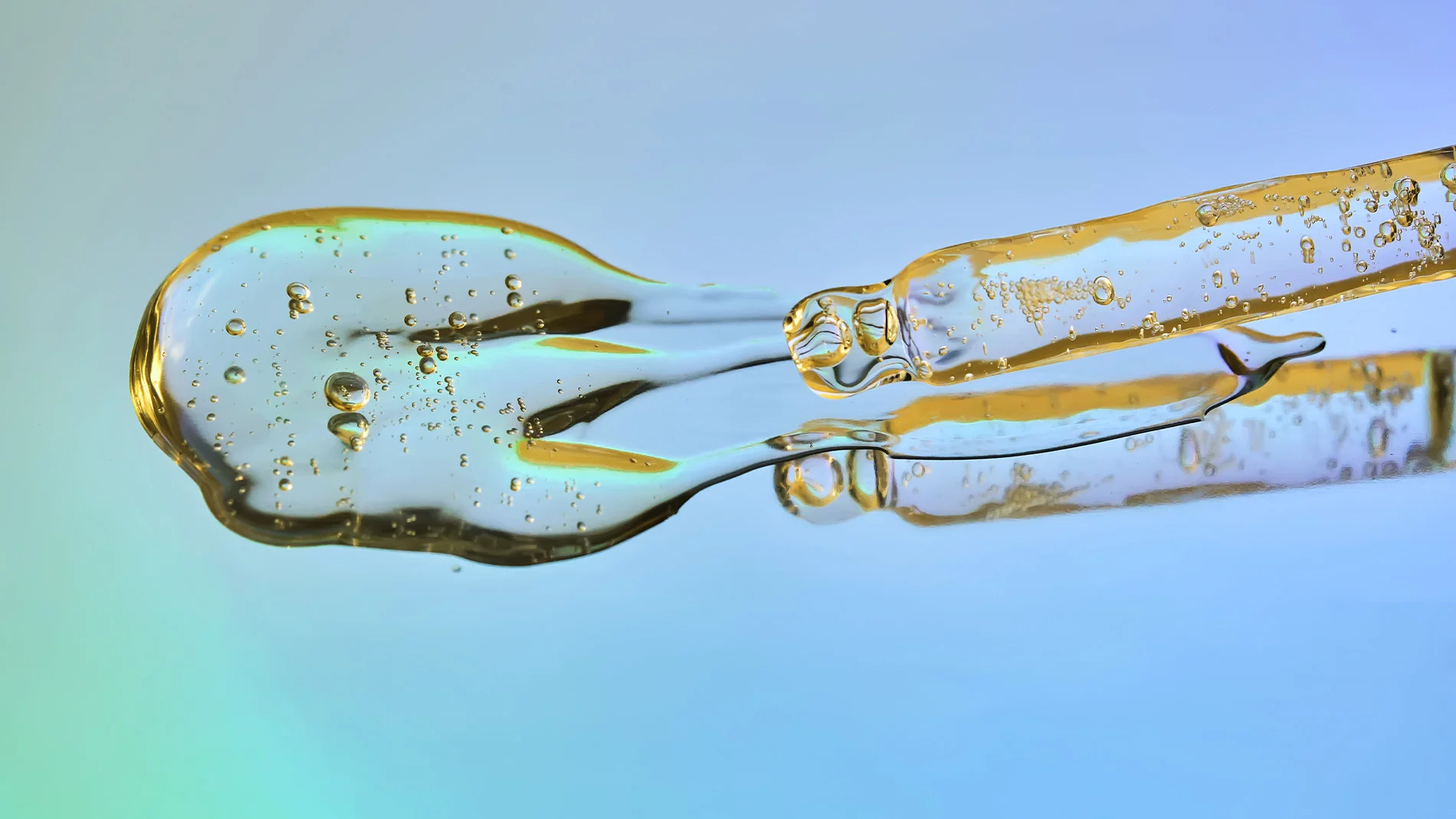 Närbild av en genomskinlig vätska med bubblor på en reflekterande yta.