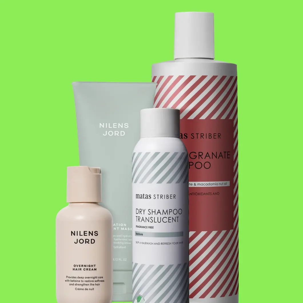 Hårvårdsprodukter från Matas Striber och Nilens Jord mot en klargrön bakgrund, bland annat Matas Striber Pomegranate Shampoo och Dry Shampoo Translucent samt Nilens Jord Overnight Hair Cream och en hårmask.
