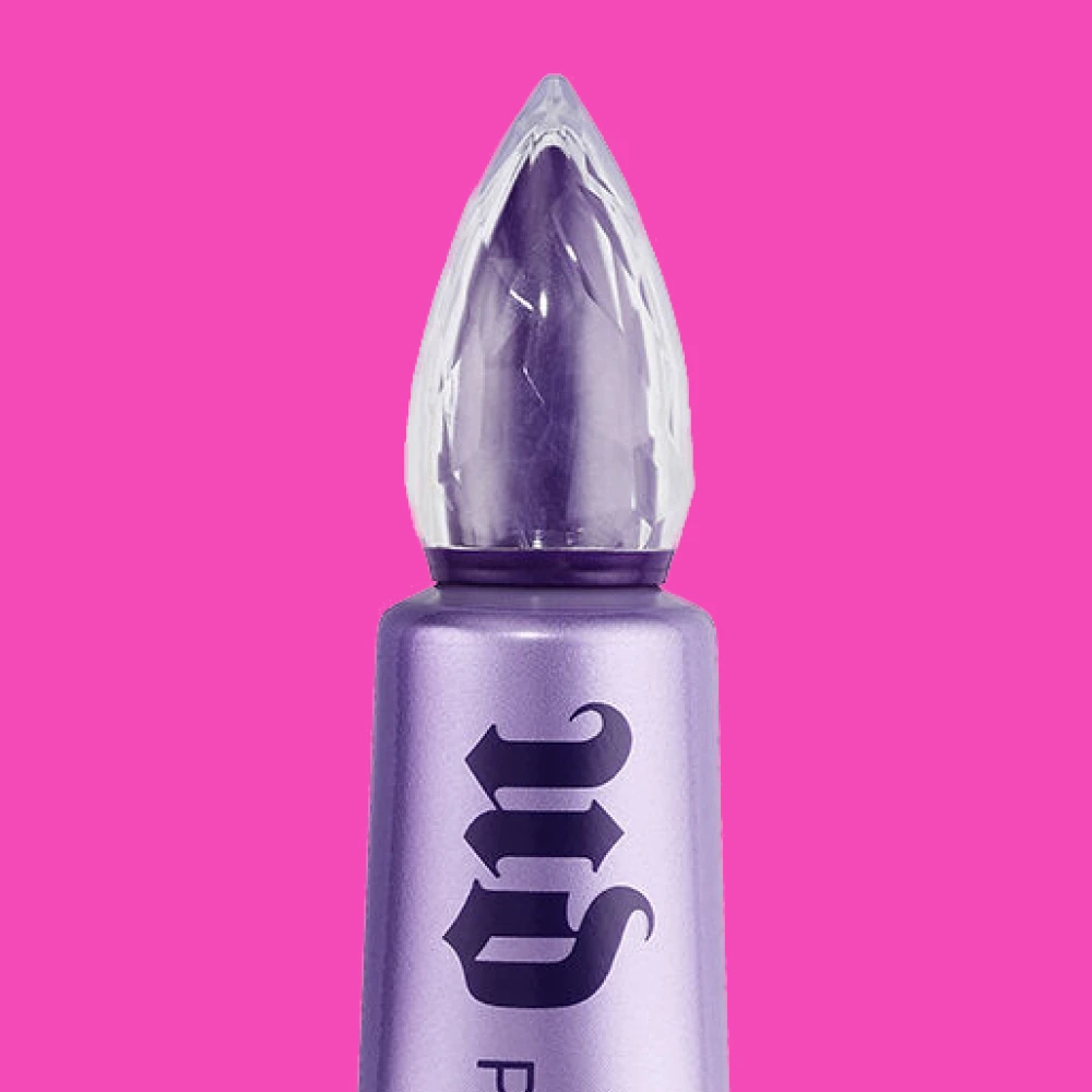  Urban Decay Primer Potion, jossa on violetti runko ja läpinäkyvä korkki, vaaleanpunaisella taustalla.