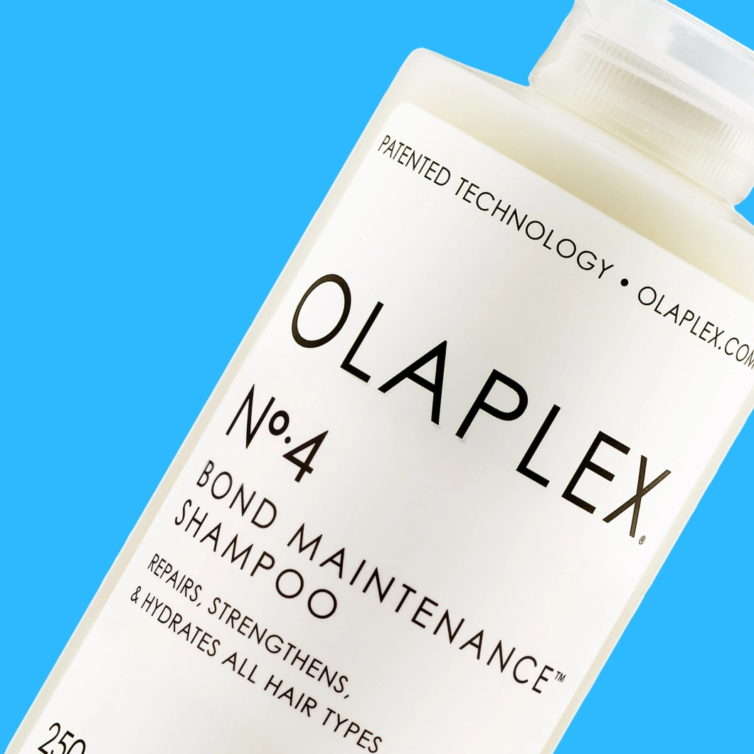 Olaplex No.4 Bond Maintenance Shampoo mot blå bakgrund. På flaskan syns texterna ”PATENTED TECHNOLOGY”, ”OLAPLEX No.4”, ”BOND MAINTENANCE SHAMPOO”, ”REPAIRS, STRENGTHENS, & HYDRATES ALL HAIR TYPES” och ”250 ml”.