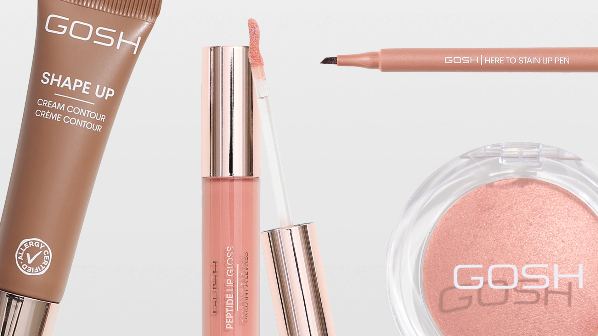 Närbild på sminkprodukter från GOSH: Shape Up Cream Contour Crème Contour med Allergy Certified-symbol, Here To Stain Lip Pen, Peptide Lip Gloss Brilliant Lip Glaze med applikator samt ett runt puderrouge med GOSH-logotyp. Produkterna visas i nude- och rosatoner mot ljus bakgrund.