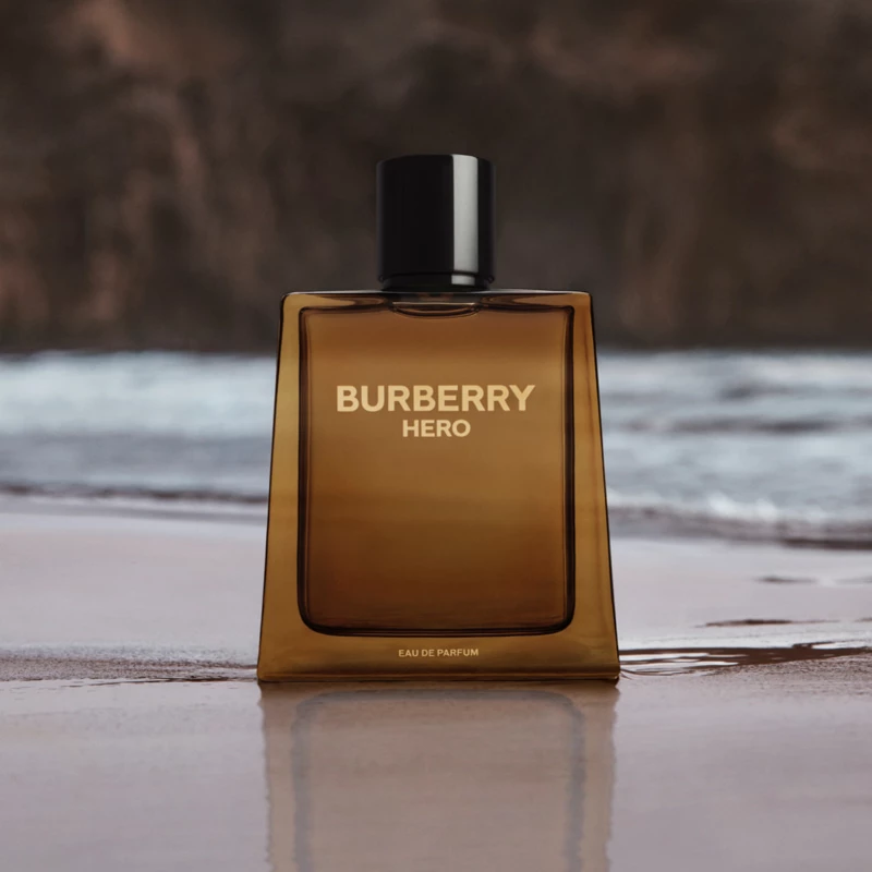 Ruskea hajuvesipullo, jonka taustalla on ranta. Pullossa lukee Burberry Hero.