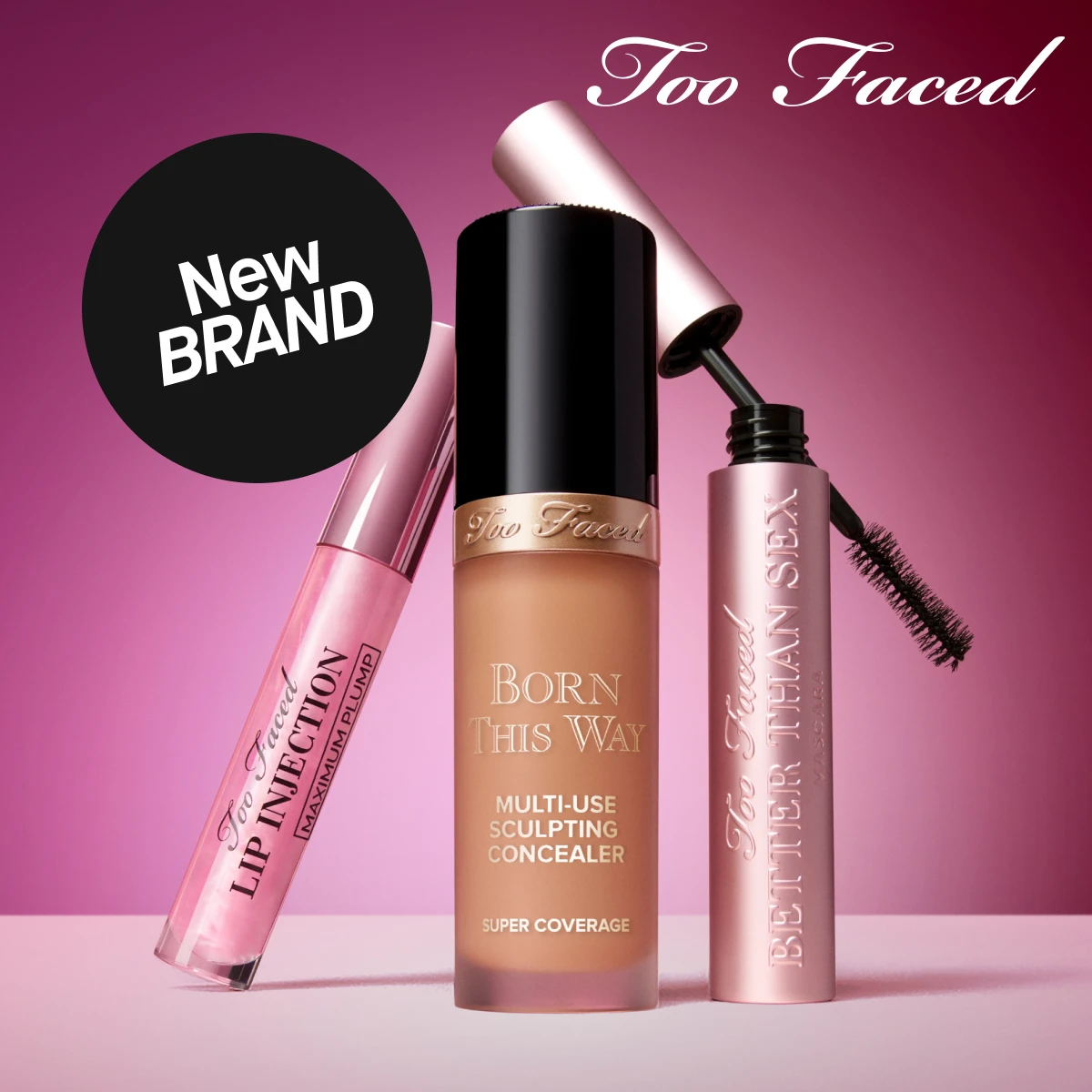 En bild som visar tre produkter från Too Faced. Produkterna inkluderar Lip Injection Maximum Plump, Born This Way Multi-Use Sculpting Concealer och Better Than Sex Mascara. Texten "BOOM! Too Faced är här!" och "New BRAND" syns på bilden,