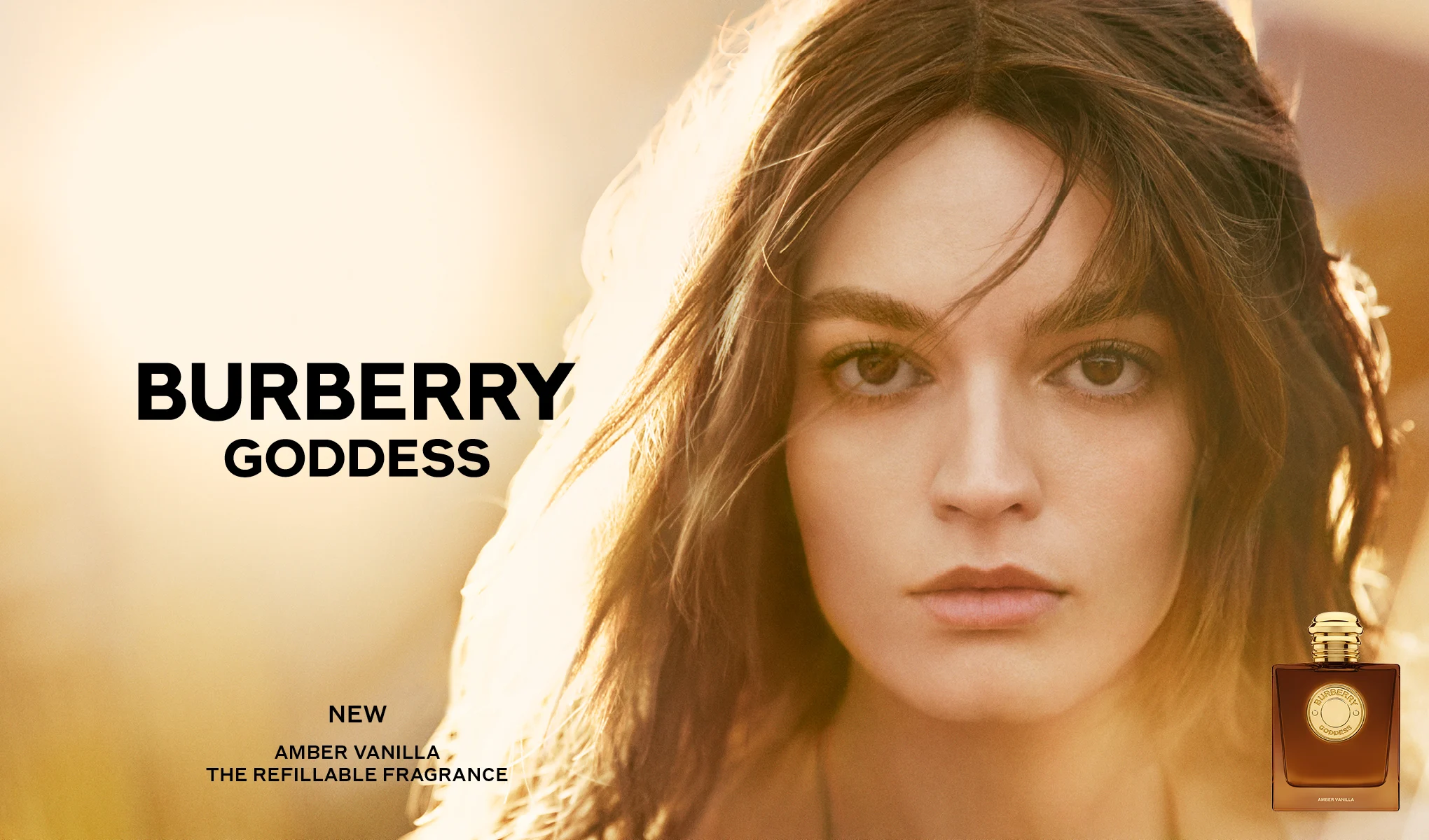 Pitkähiuksinen henkilö lämpimästi valaistua taustaa vasten ja Burberry Goddess Amber Vanilla -hajuvesipullo oikeassa alakulmassa. Kuvassa näkyvät tekstit ”BURBERRY GODDESS”, ”NEW”, ”AMBER VANILLA” ja ”THE REFILLABLE FRAGRANCE”.