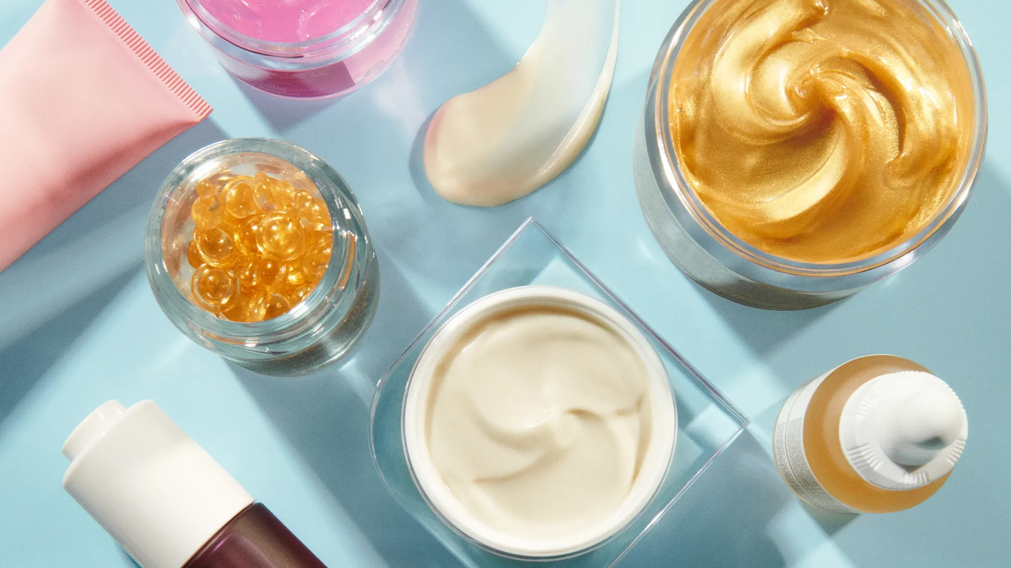 Olika skincareprodukter på ett blått underlag.