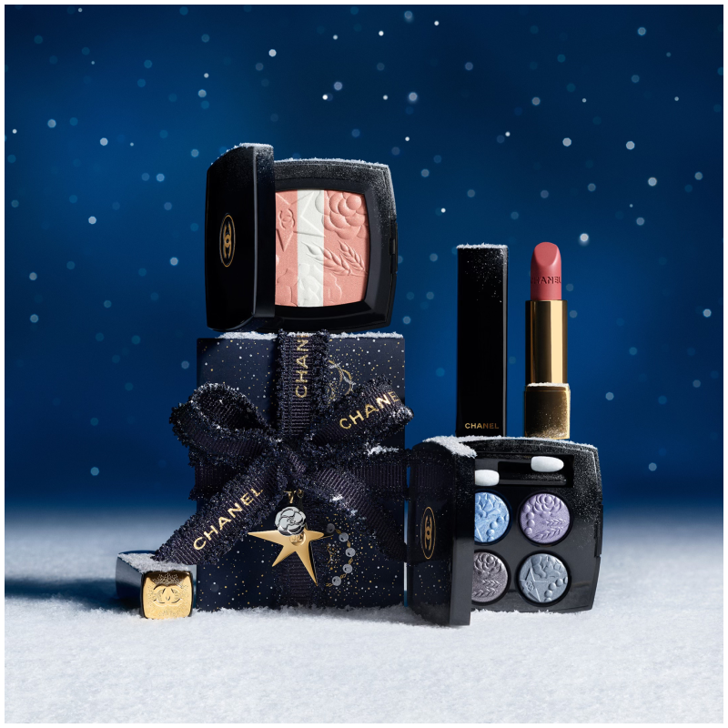 Chanel sminkeprodukter, inkludert rouge, leppestift og øyenskygge, på en snødekt bakgrunn med stjernehimmel.