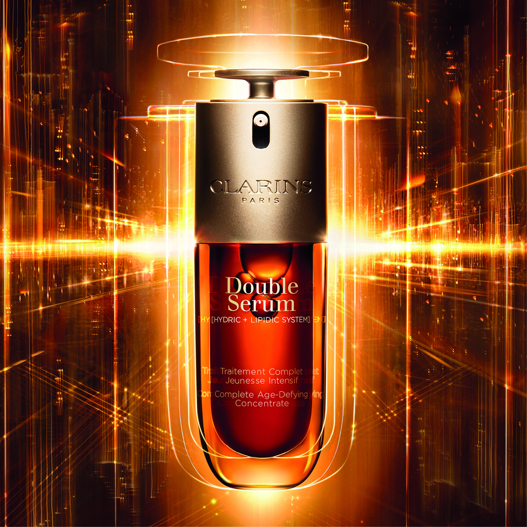 Clarins Double Serum -pullo, jossa on hehkuva, kultainen tausta. Pullossa on tyylikäs muotoilu, jossa on teksti ”Double Serum” ja ”Hydric + Lipidic System”.
