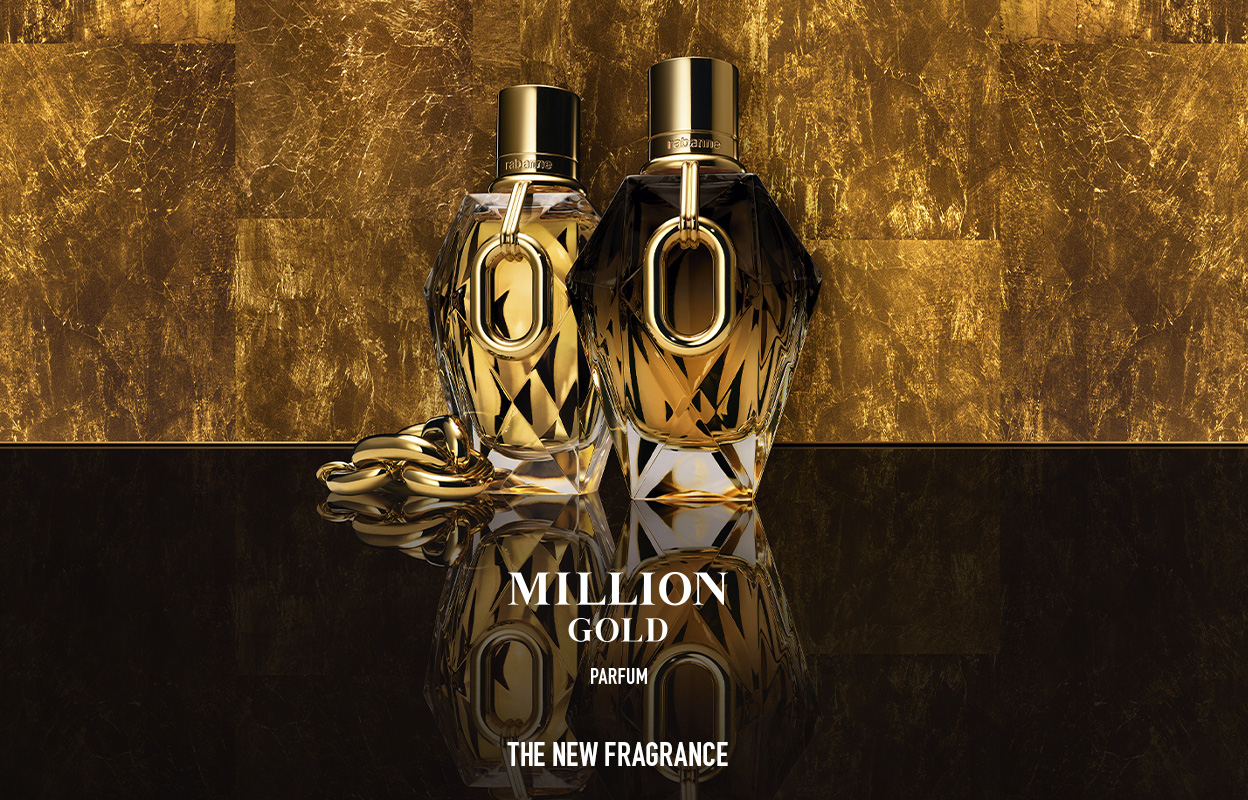 To flasker av parfymen "Million Gold" står på en blank overflate, omgitt av en gyllen bakgrunn. Flaskene har en elegant design med gullfargede detaljer. Ved siden av flaskene ligger en gullkjede. Teksten på bildet lyder: "Million Gold Parfum. The New Fragrance".
