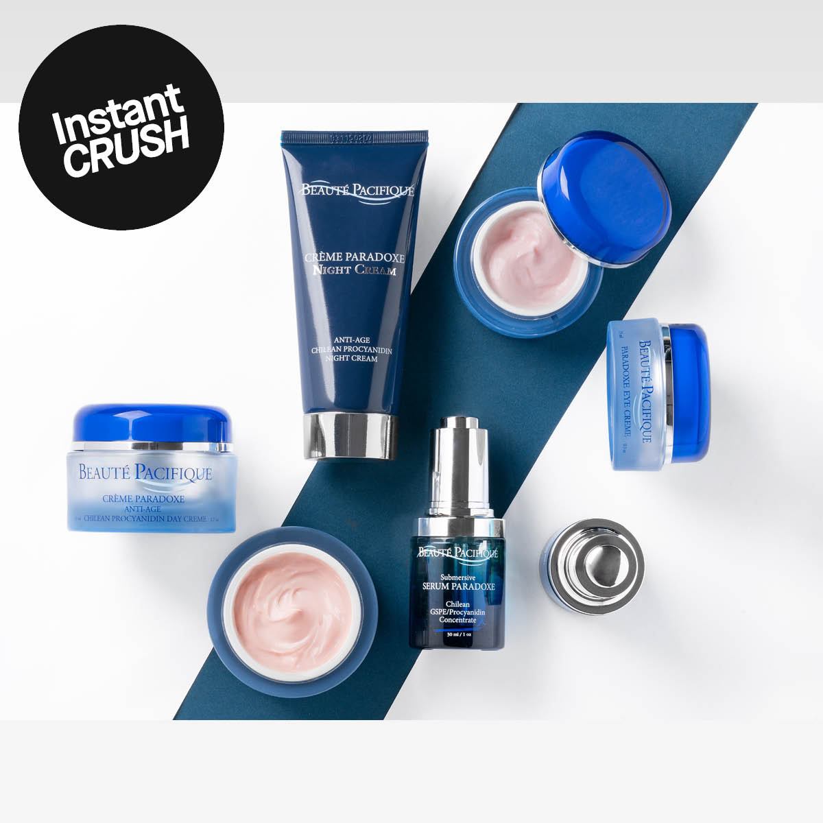 Beauté Pacifique-produkter, inklusive Crème Paradoxe Night Cream, Crème Paradoxe Day Cream, Submersive Serum Paradoxe och Body Lotion, placerade på en vit och blå bakgrund.
