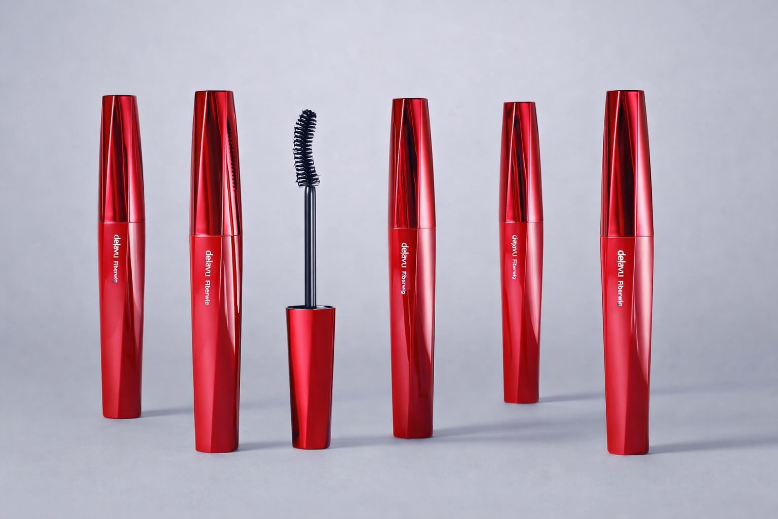 Fem røde mascaraer fra Dejavu står på rekke mot en lys grå bakgrunn. Én mascara er åpnet og viser en svart børste i midten.