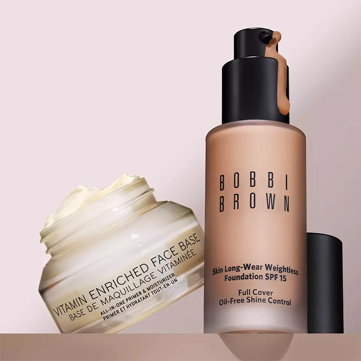 Kaksi Bobbi Brownin meikkituotetta vaaleanpunaisella taustalla. Purkki "Vitamin Enriched Face Base" ja pullo "Skin Long-Wear Weightless Foundation SPF 15".
