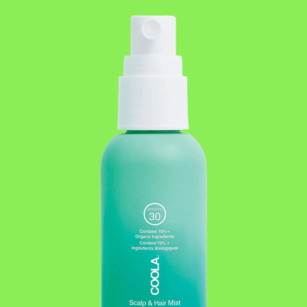 Sprayflaska märkt “COOLA Scalp & Hair Mist SPF/FPS 30 Contains 70%+ Organic Ingredients” mot grön bakgrund.