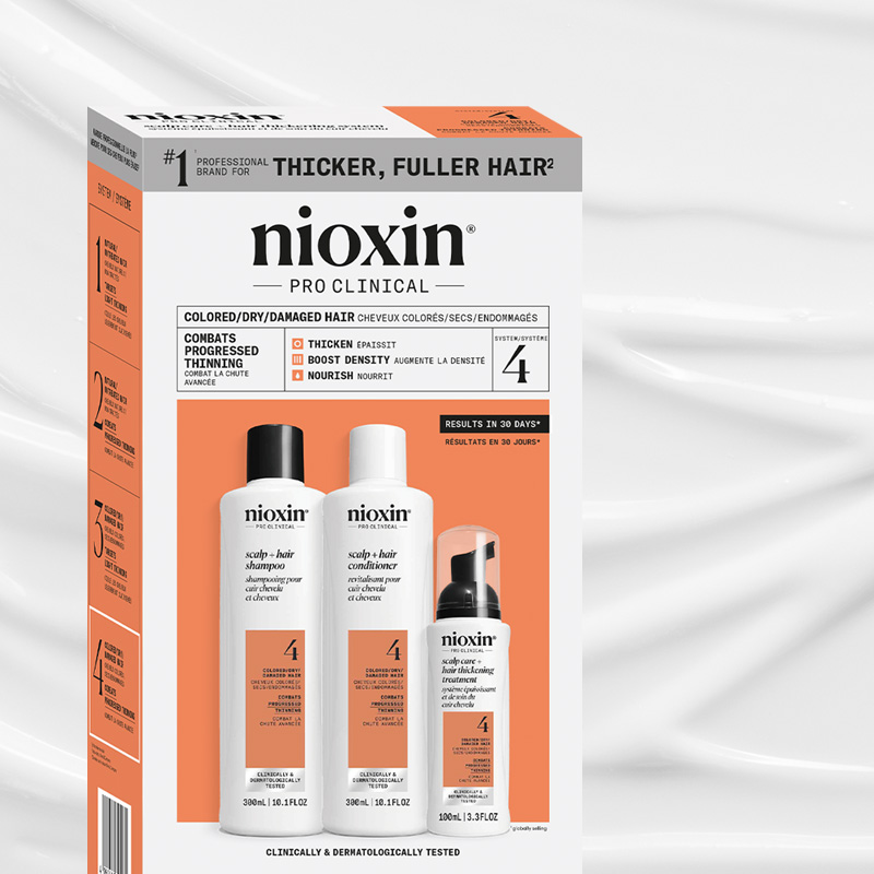 Nioxin Pro Clinical System 4 -pakkaus värjätyille/kuiville/vahingoittuneille hiuksille, sisältäen shampoon, hoitoaineen ja käsittelyn valkoisissa pulloissa, joissa on oranssit etiketit.