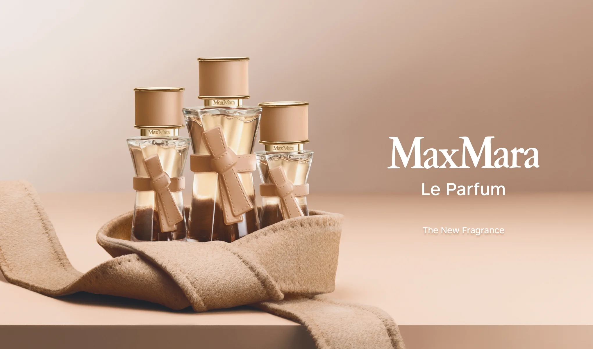 Kolme Max Mara Le Parfum -tuoksupulloa beigen kankaan päällä.