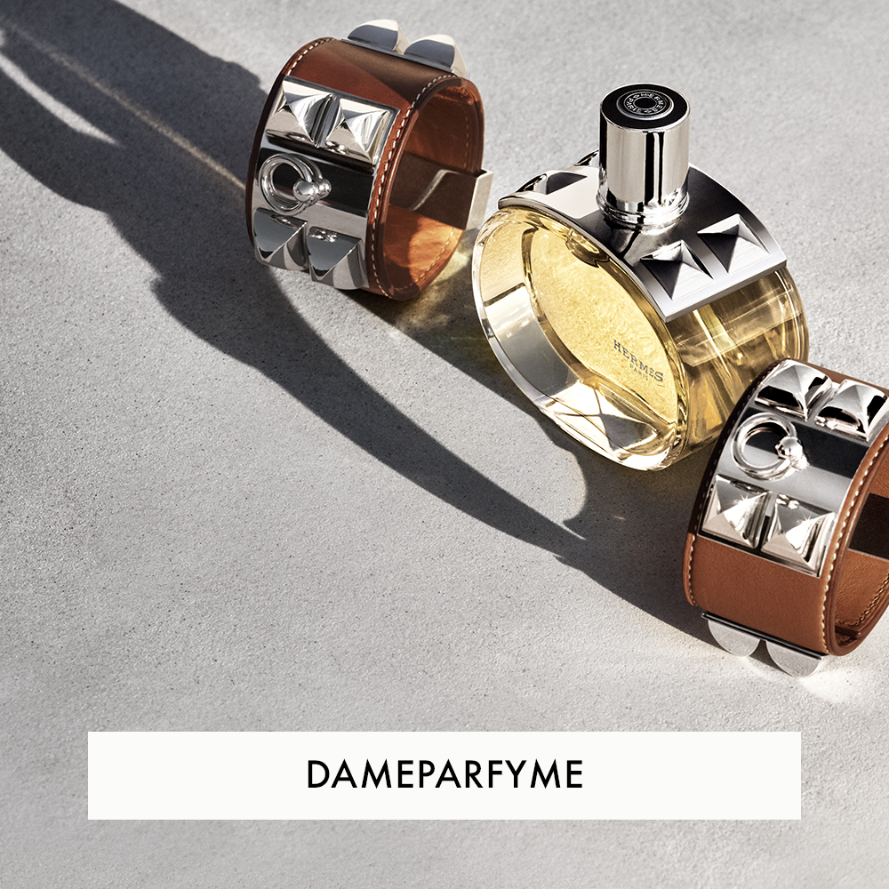 Dameparfyme fra Hermès, med en lys gul væske, plassert på en grå overflate sammen med to armbånd med metalliske detaljer. Teksten "DAMEPARFYME" vises nederst.