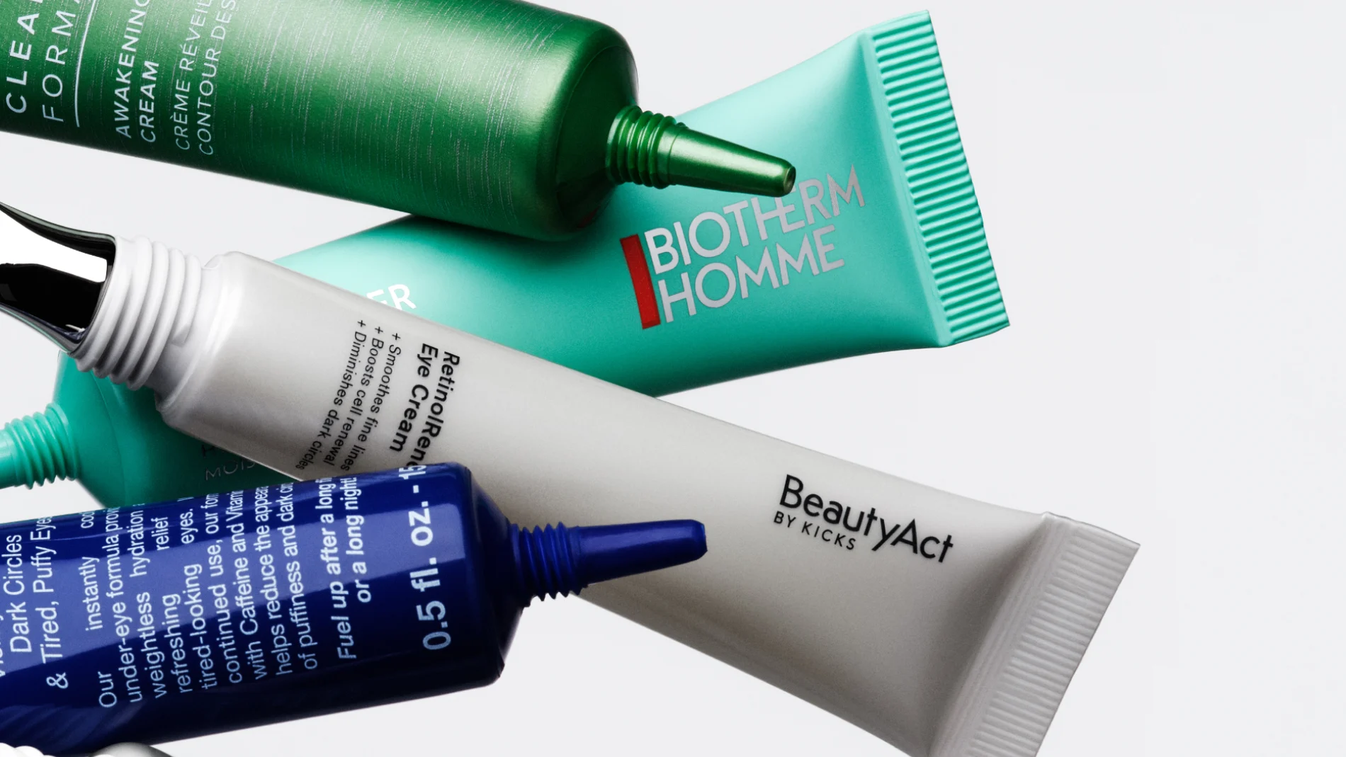 Fire tuber med øyekrem plassert diagonalt mot lys bakgrunn. En grønn tube med teksten «Awakening Eye Cream» og «Crème Réveil Contour des Yeux», en turkis tube med teksten «BIOTHERM HOMME», en grå tube med teksten «BeautyAct by KICKS» og «RetinolRenew Eye Cream», samt en blå tube med teksten «0.5 fl. oz».