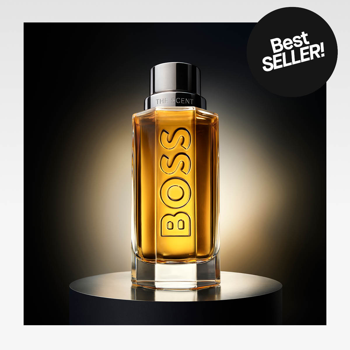 Boss-hajuvesipullo "The Scent" seisoo valaistulla jalustalla, tummaa taustaa vasten. Musta tarra, jossa lukee "Bestseller".