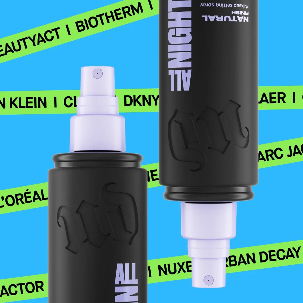 To svarte flasker med Urban Decay All Nighter Natural Finish Makeup Setting Spray mot blå bakgrunn med grønne bånd som viser merkene BeautyAct, Biotherm, Calvin Klein, DKNY, L’Oréal, Nuxe og Urban Decay. Synlig tekst på flaskene: «UD», «ALL NIGHTER», «NATURAL FINISH» og «Makeup setting spray».