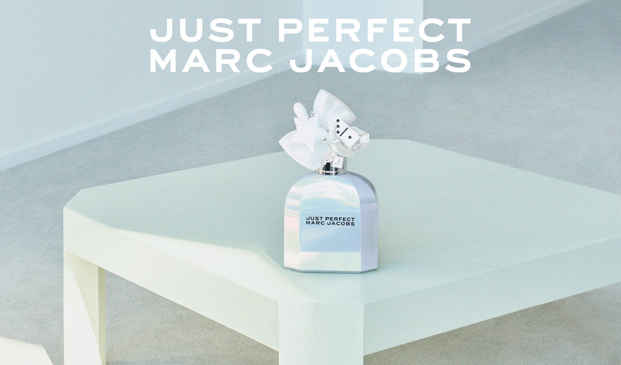 Marc Jacobs Just Perfect -hajuvesipullo valkoisella rusetilla ja dominonappi-korkilla. Teksti: JUST PERFECT MARC JACOBS.
