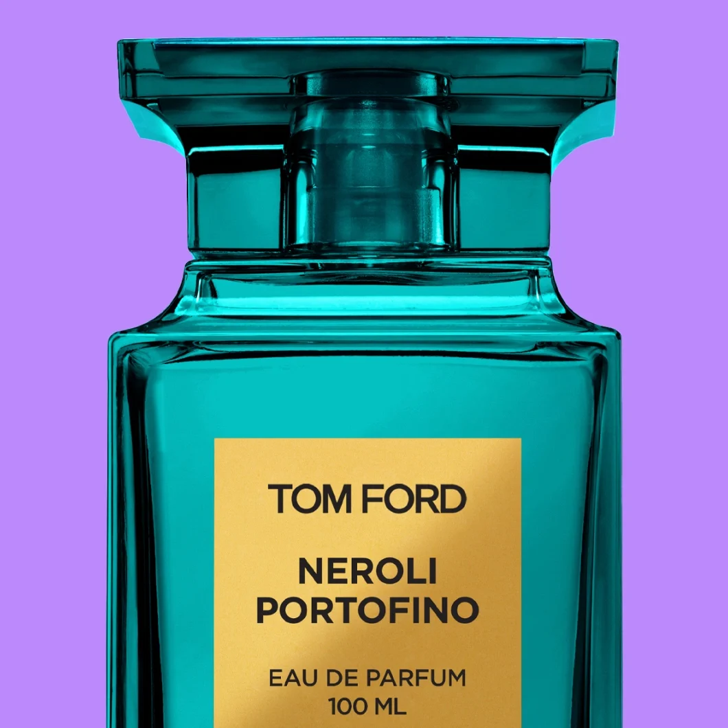 Nærbilde av Tom Ford Neroli Portofino Eau de Parfum i en turkis glassflaske med gullfarget etikett og teksten «TOM FORD NEROLI PORTOFINO EAU DE PARFUM 100 ML», mot lilla bakgrunn.
