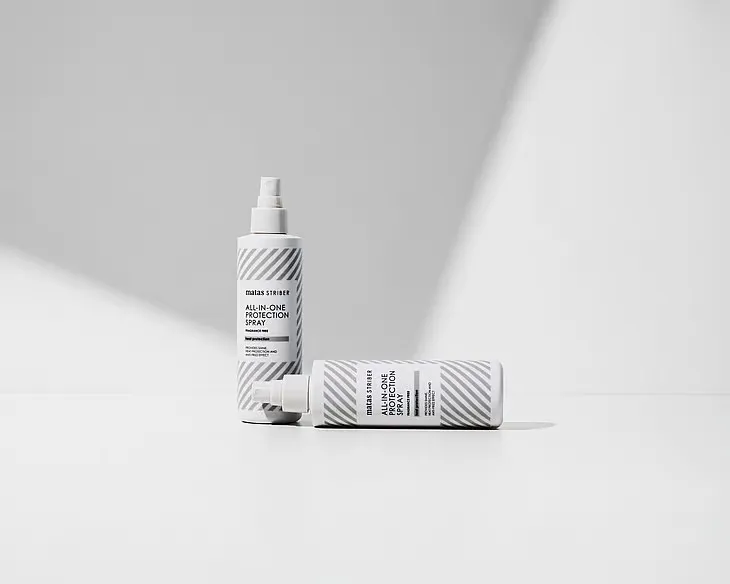“Matas Striber All-In-One Protection Spray vaalealla minimalistisella taustalla, yksi pullo pystyssä ja toinen vaakatasossa korostaen tuotteen puhdasta ja modernia ilmettä.”