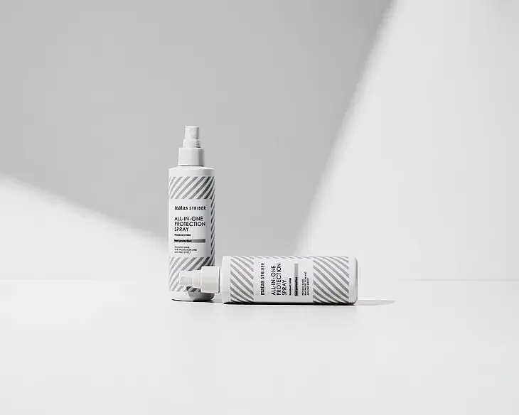 “Matas Striber All-In-One Protection Spray vaalealla minimalistisella taustalla, yksi pullo pystyssä ja toinen vaakatasossa korostaen tuotteen puhdasta ja modernia ilmettä.”