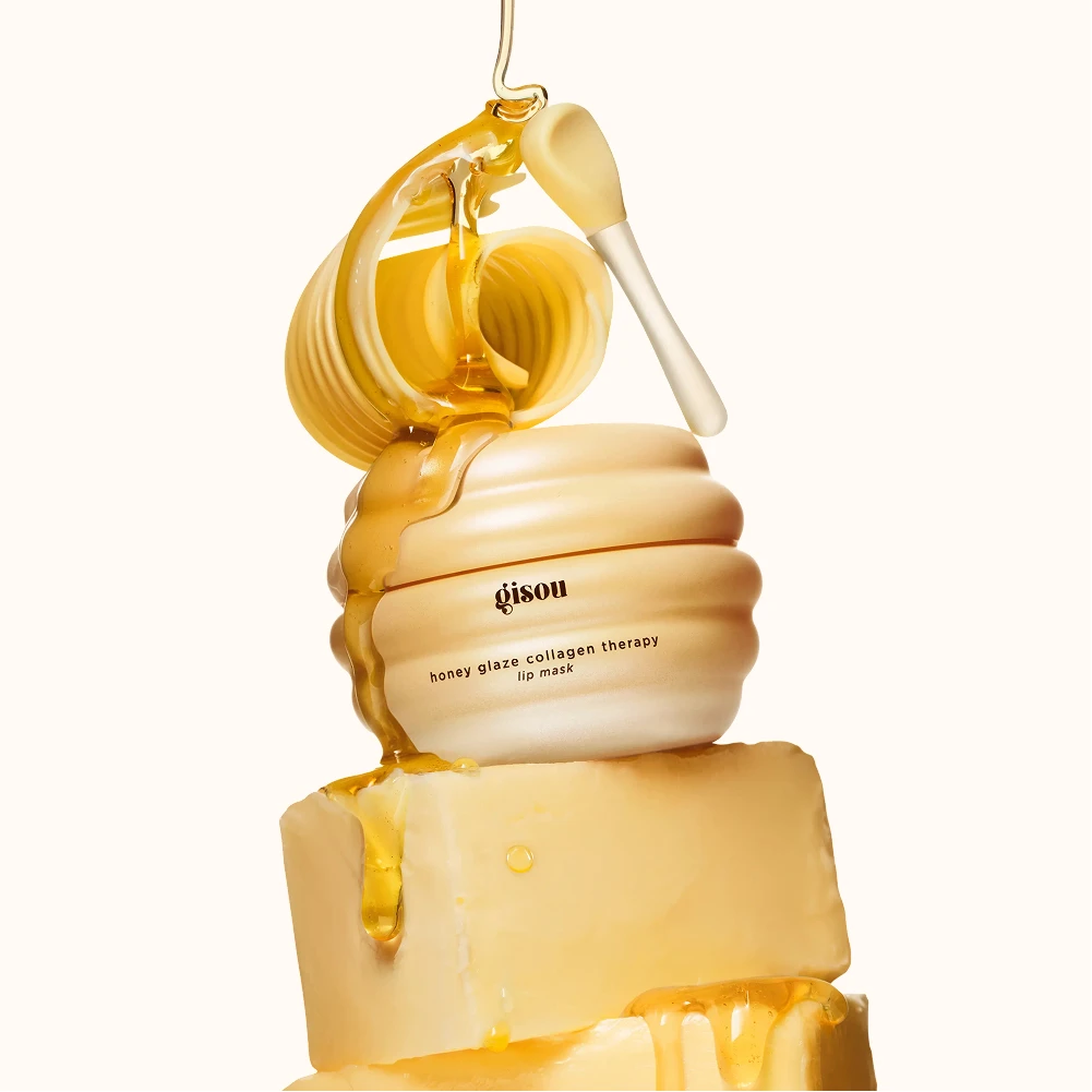 Gisou Honey Glaze Collagen Therapy Lip Mask-krukke, formet som honning, med honning dryppende over den og ned på bivoks.