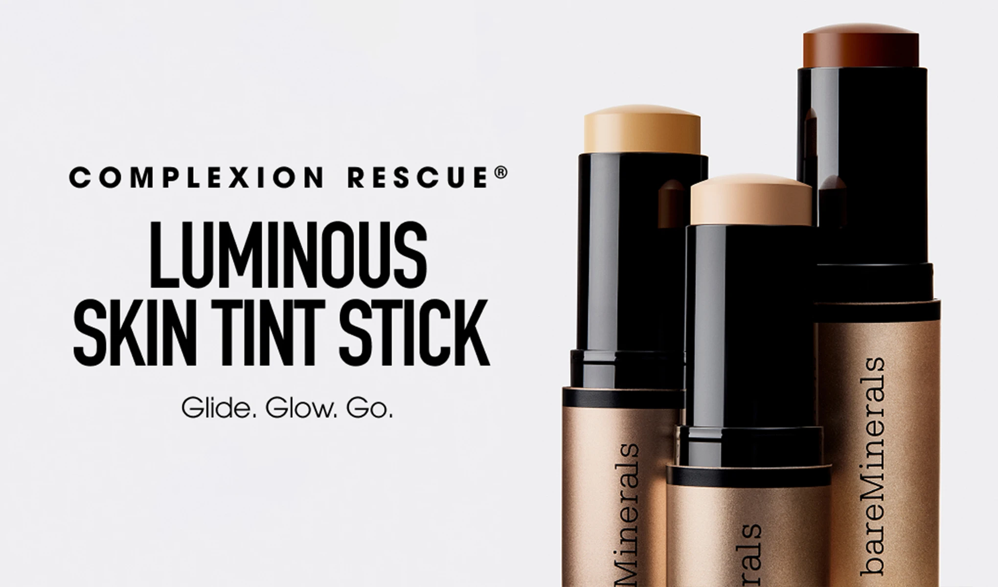 bareMinerals Complexion Rescue Luminous Skin Tint Stick näkyy kolmessa sävyssä stick-muotoisena mustassa ja pronssinvärisessä pakkauksessa. Vaalealla taustalla näkyvät tekstit “COMPLEXION RESCUE”, “LUMINOUS SKIN TINT STICK” ja “Glide. Glow. Go.”