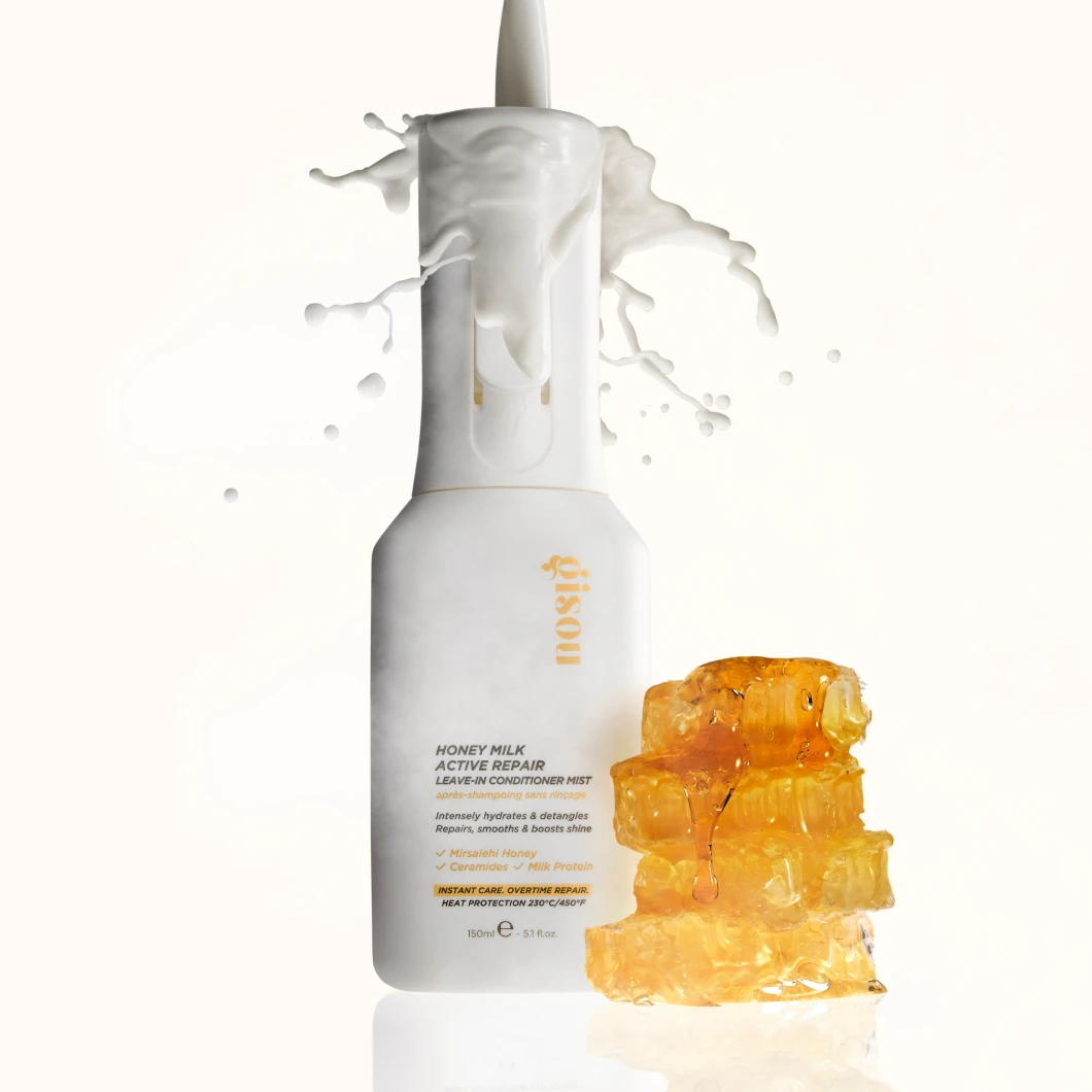 Vit Gisou Honey Milk Active Repair Leave-In Conditioner Mist-flaska med mjölkstänk och honungskaka som droppar honung.