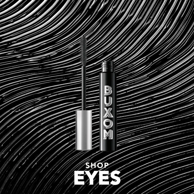 Buxom mascaratub och borste på en bakgrund av mascarastreck. Text: Shop Eyes.