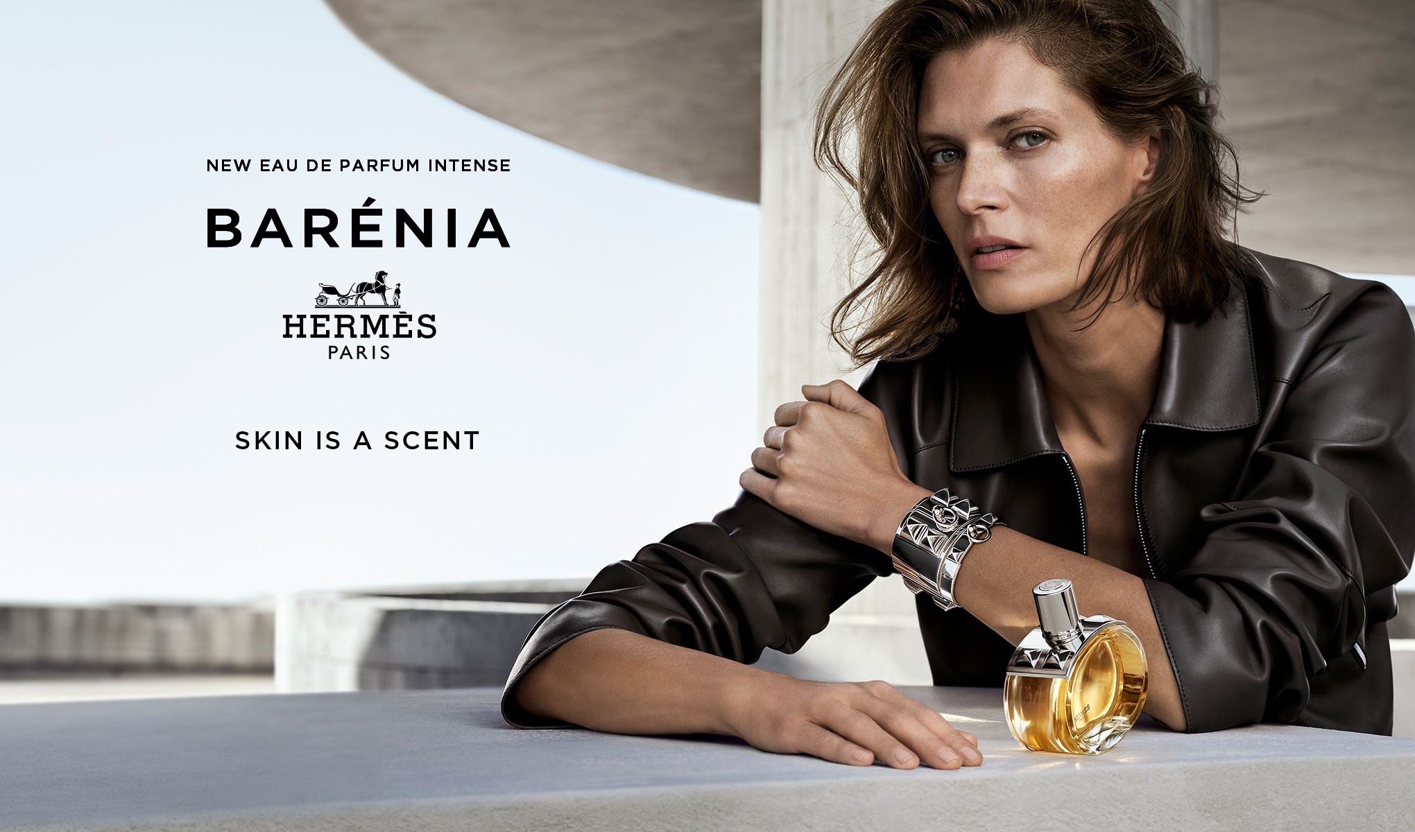 Hermès Barénia Eau de Parfum Intense-flaska, placerad på ett bord bredvid en person i en svart läderjacka.